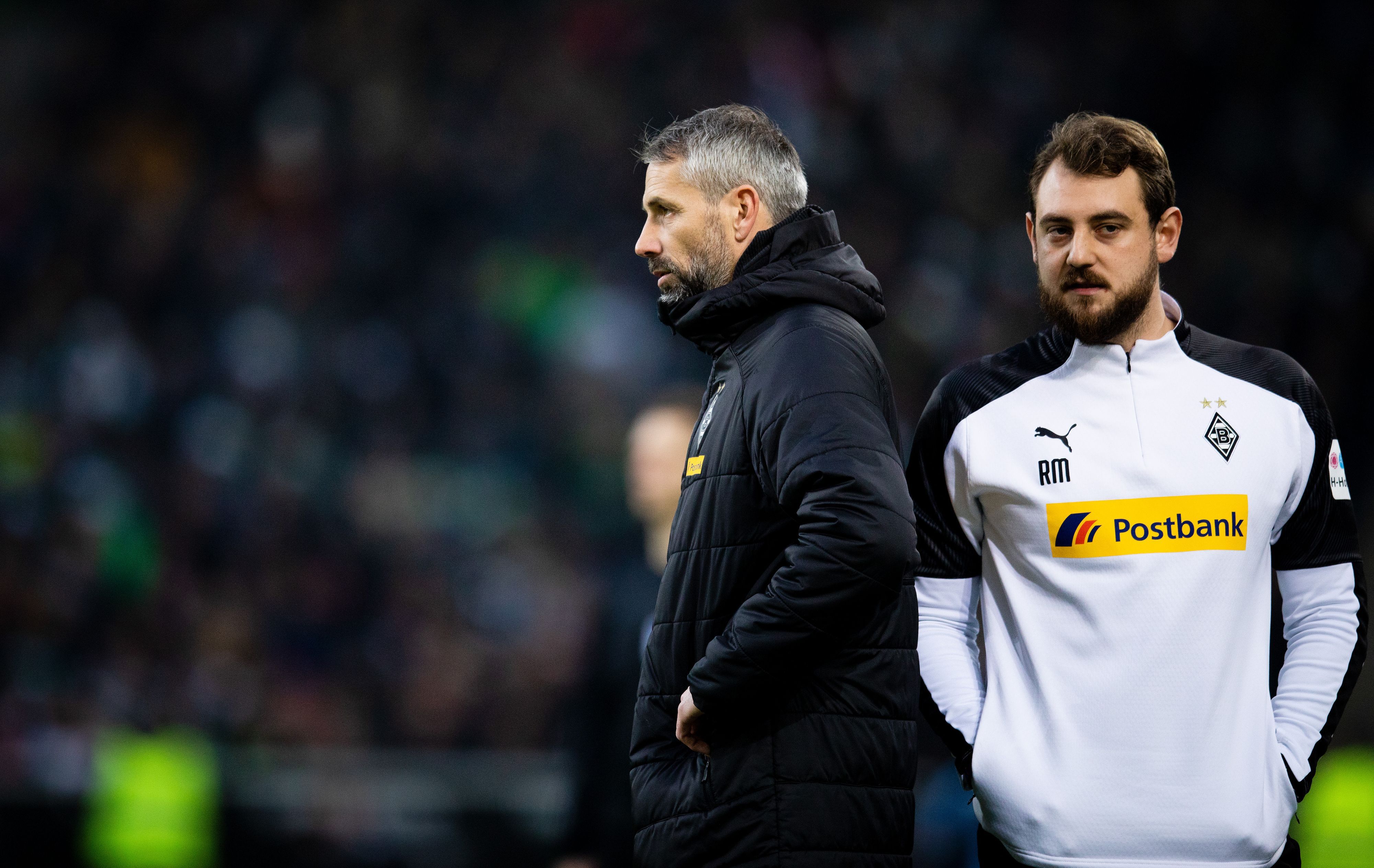 René Maric steht hinter Marco Rose in einer Gladbach-Jacke.