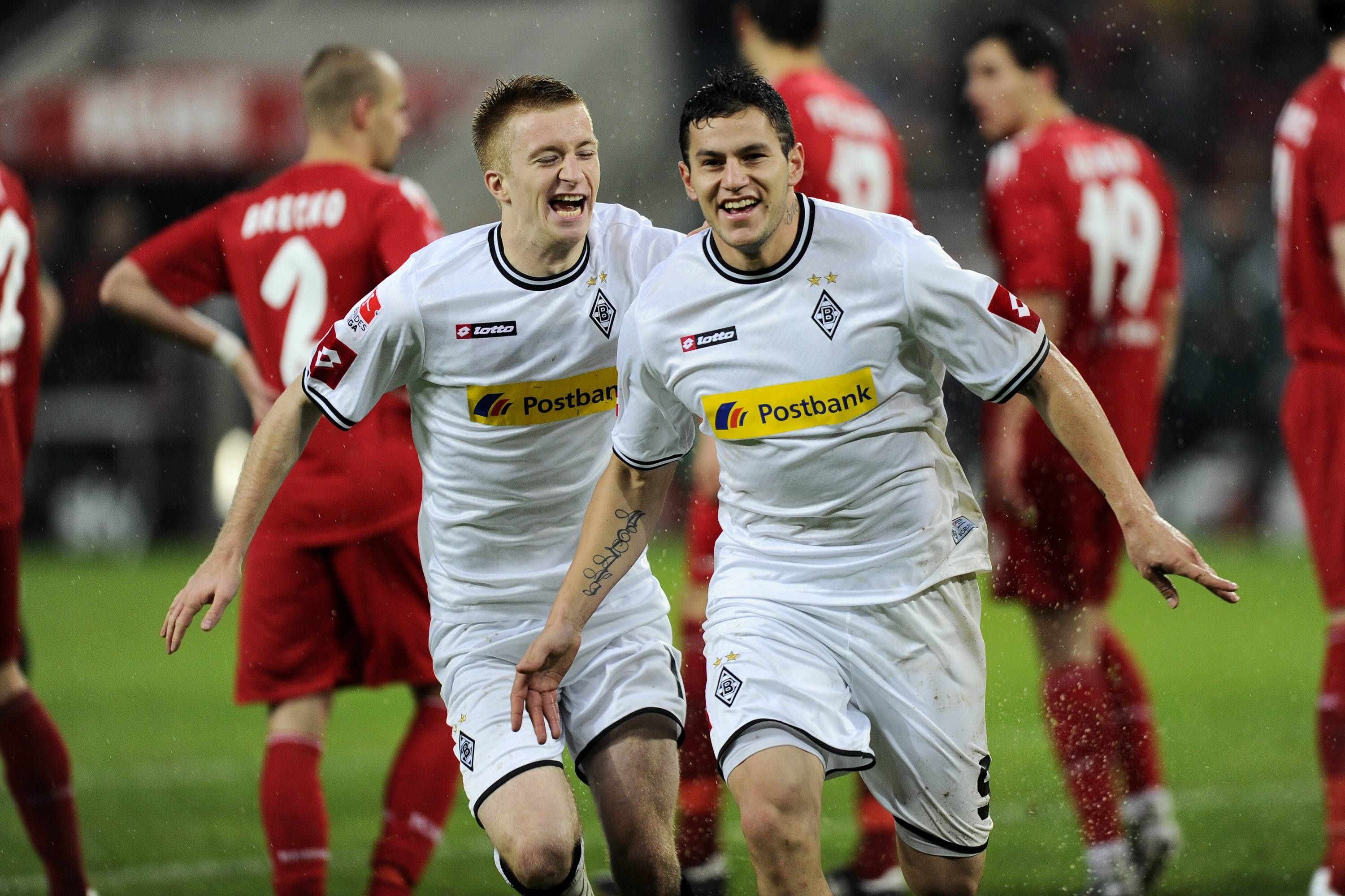 Raul Bobadilla und Marco Reus jubeln über ein Tor. Im Hintergrund sind enttäuschte Spieler des 1. FC Köln zu sehen.