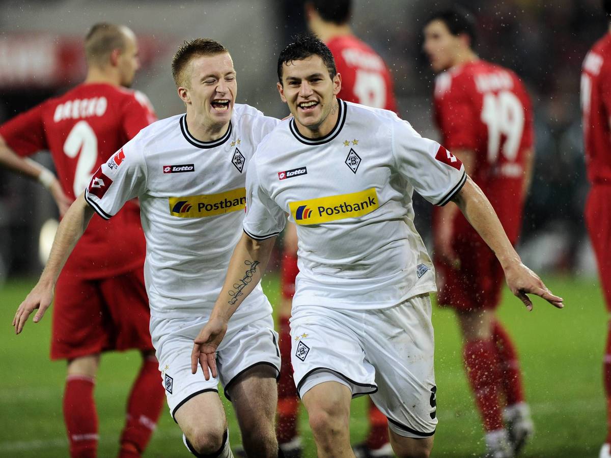 Raul Bobadilla und Marco Reus jubeln über ein Tor. Im Hintergrund sind enttäuschte Spieler des 1. FC Köln zu sehen.