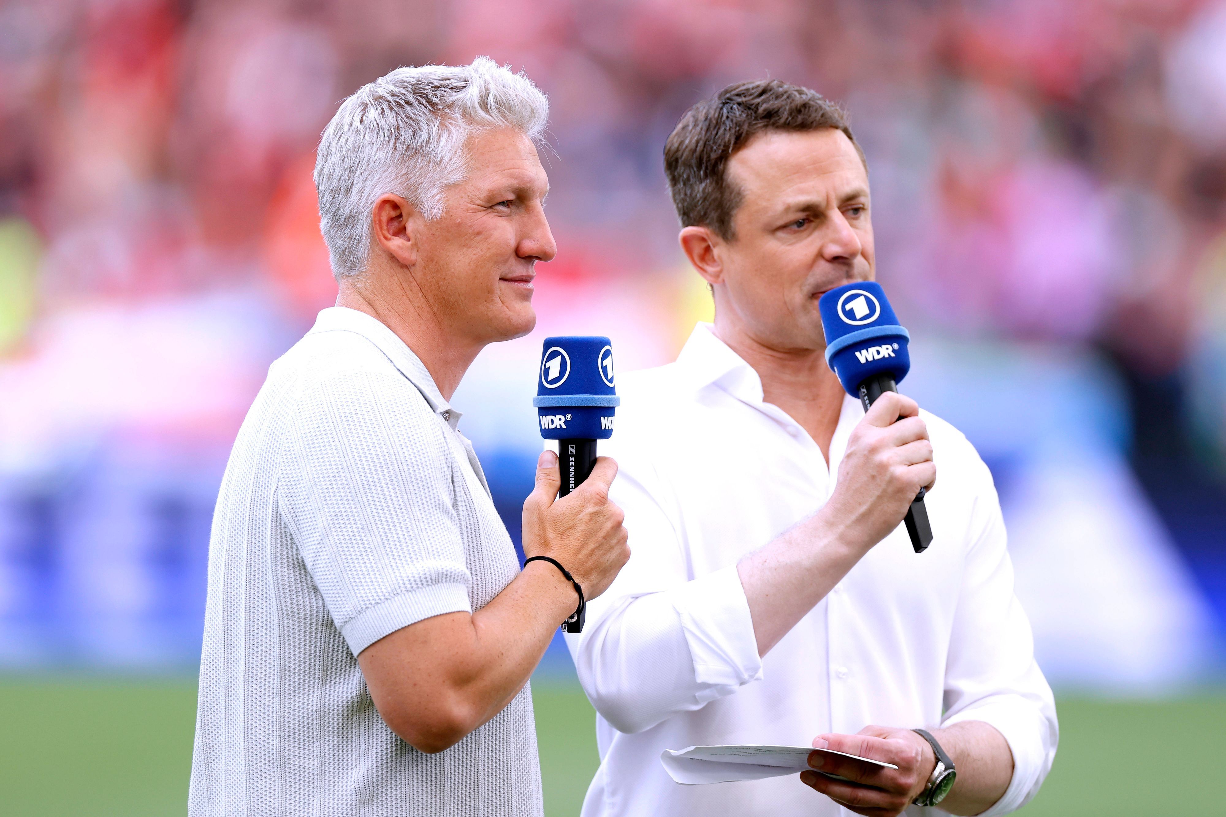 TV-Experte Bastian Schweinsteiger und ARD-Moderator Alexander Bommes stehen beim EM-Spiel Ungarn gegen Deutschland am Platz und sprechen in ihre Mikrofone.