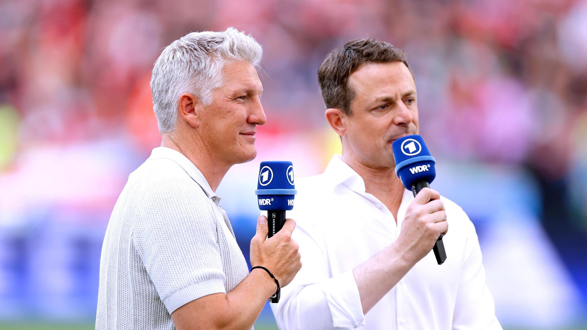 TV-Experte Bastian Schweinsteiger und ARD-Moderator Alexander Bommes stehen beim EM-Spiel Ungarn gegen Deutschland am Platz und sprechen in ihre Mikrofone.
