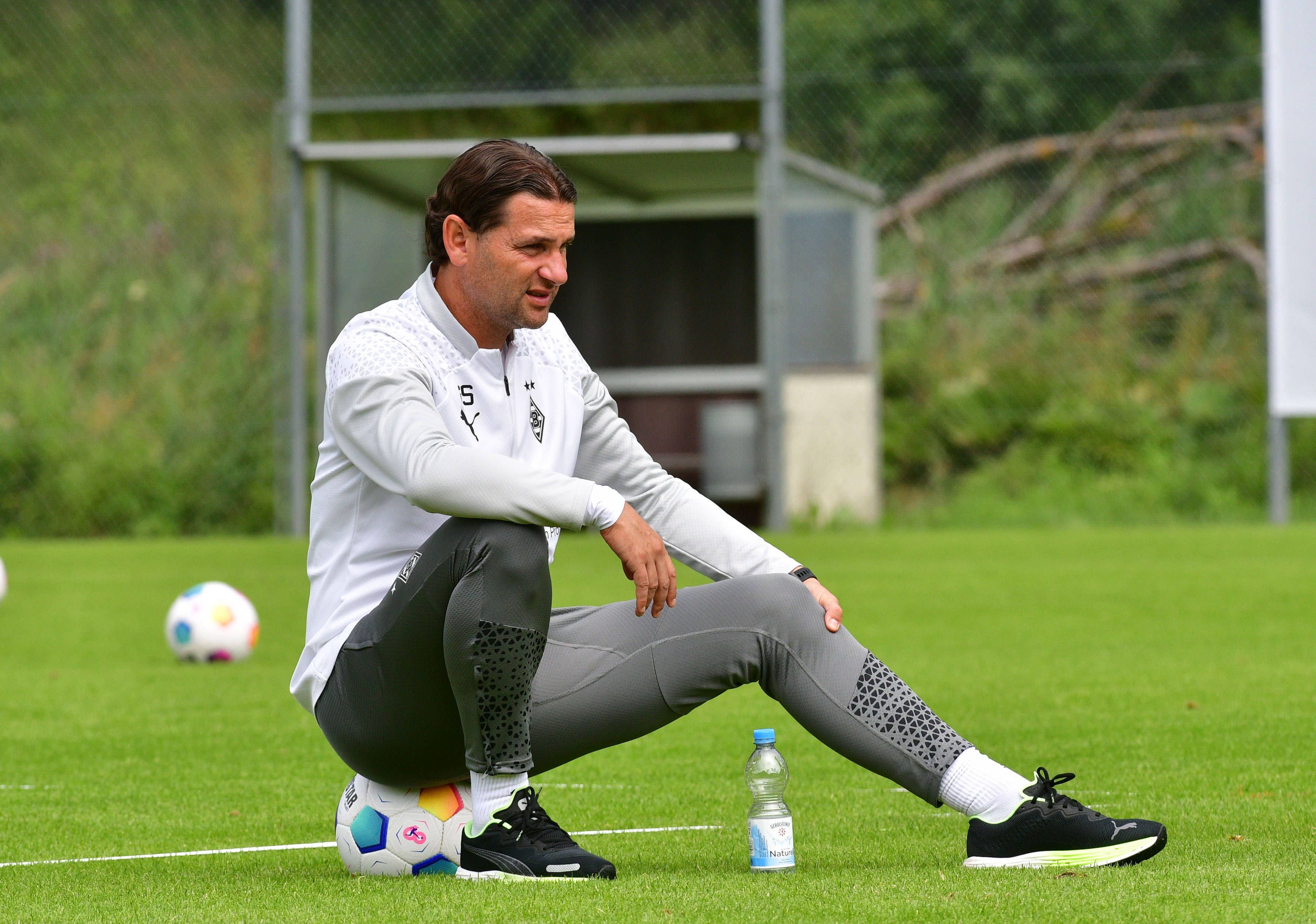 Borussia Mönchengladbachs Trainer Gerardo Seoane sitzt auf einem Ball und beobachtet die Trainingseinheit.