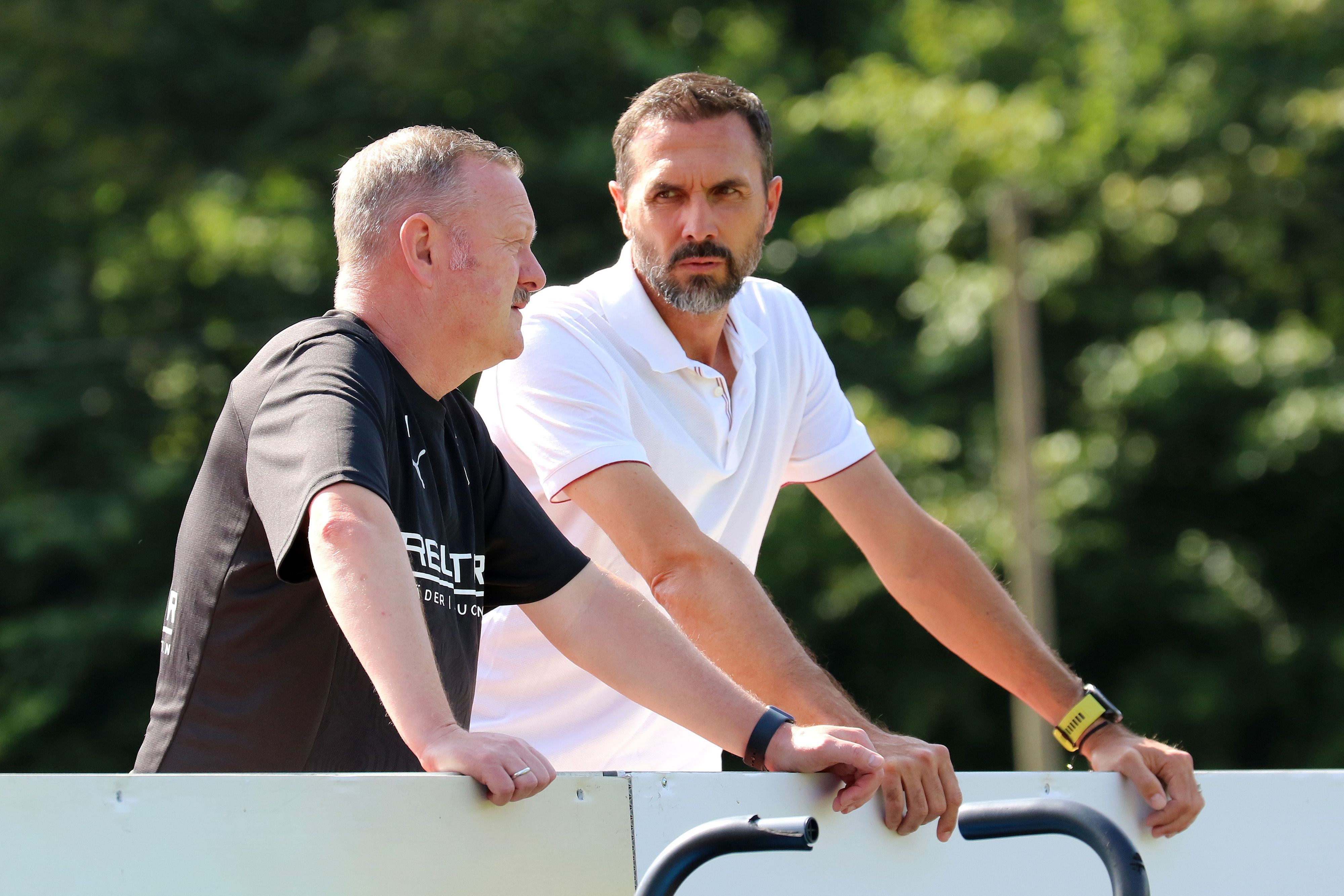Martin Stranzl und Roland Virkus stehen beim Training von Borussia Mönchengladbach neben dem Platz und unterhalten sich.