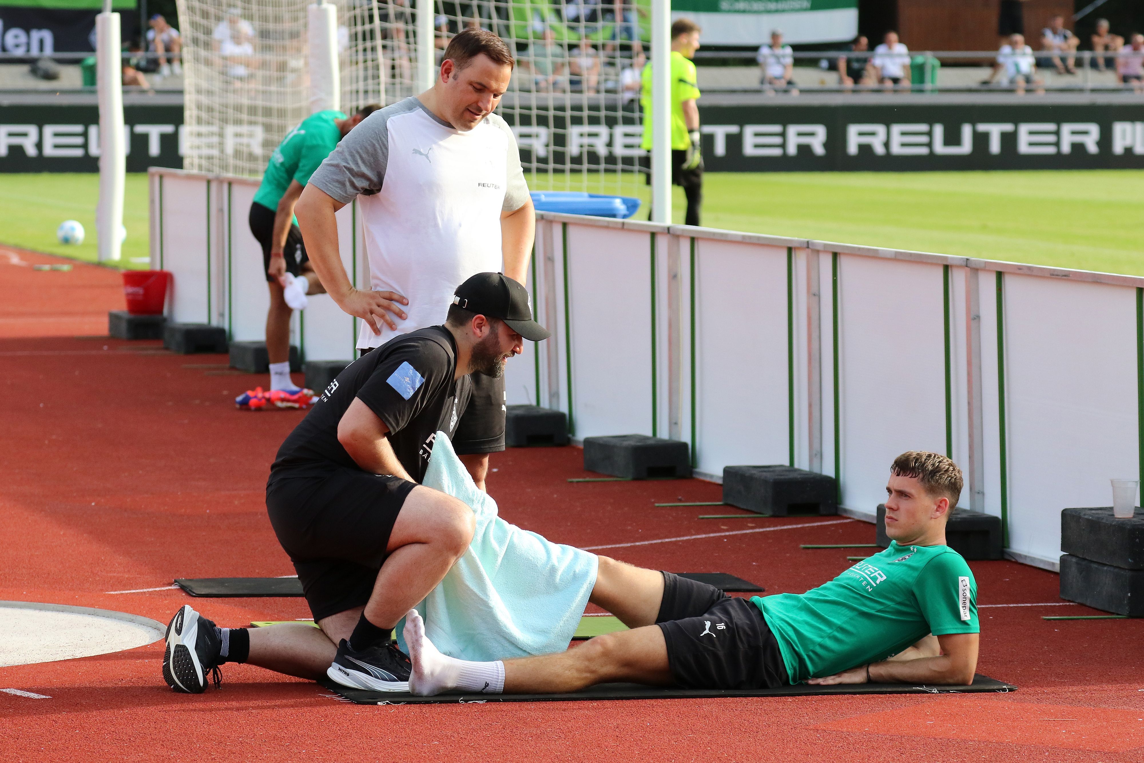 Borussia Mönchengladbachs Philipp Sander liegt auf dem Boden und lässt sich von einem Physiotherapeuten am rechten Fuß behandeln.
