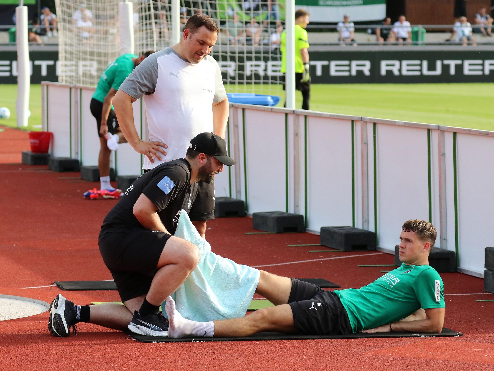 Borussia Mönchengladbachs Philipp Sander liegt auf dem Boden und lässt sich von einem Physiotherapeuten am rechten Fuß behandeln.