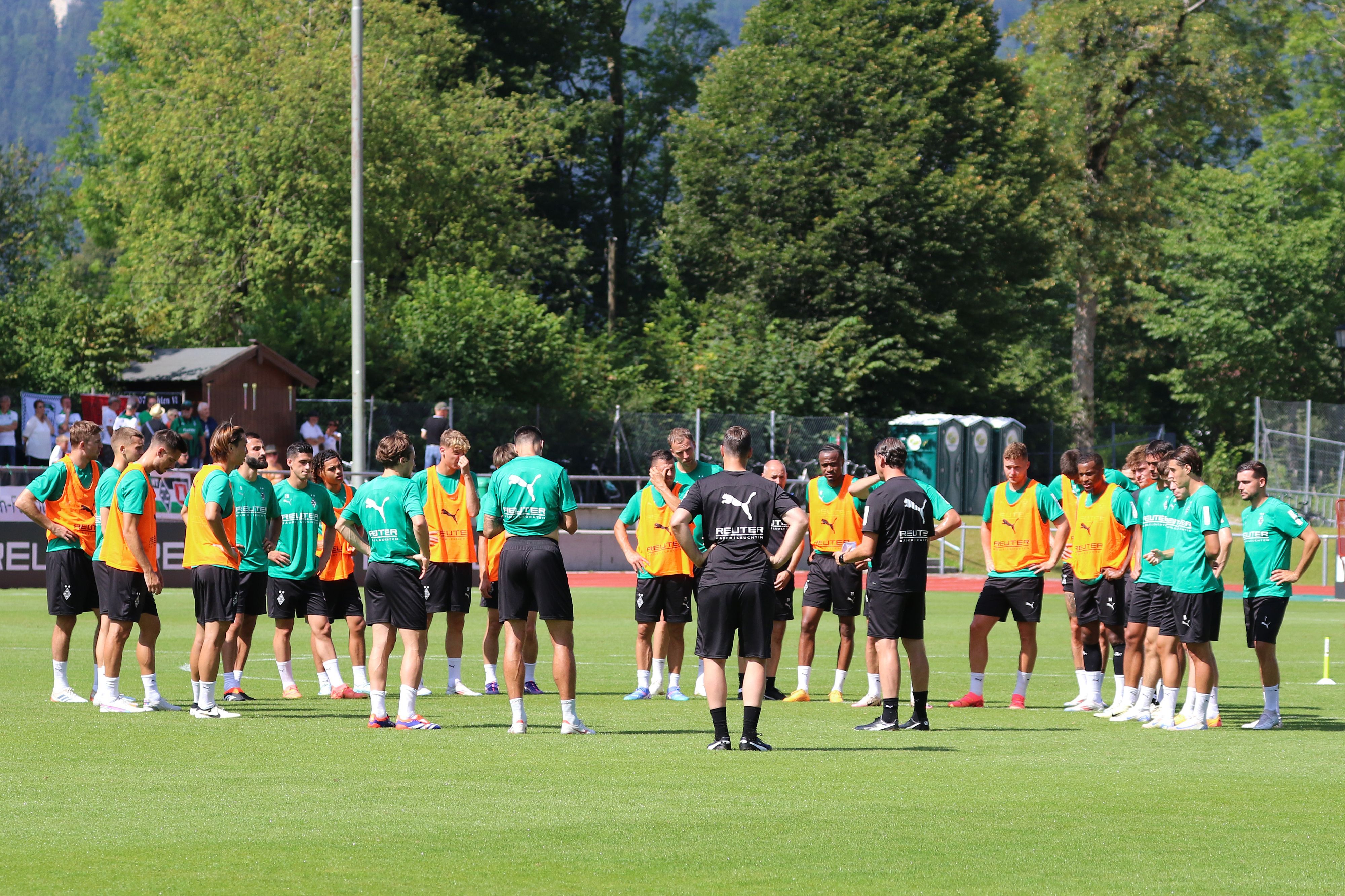 Die Spieler und Trainer von Borussia Mönchengladbach stehen auf dem Trainingsplatz im Kreis zusammen.