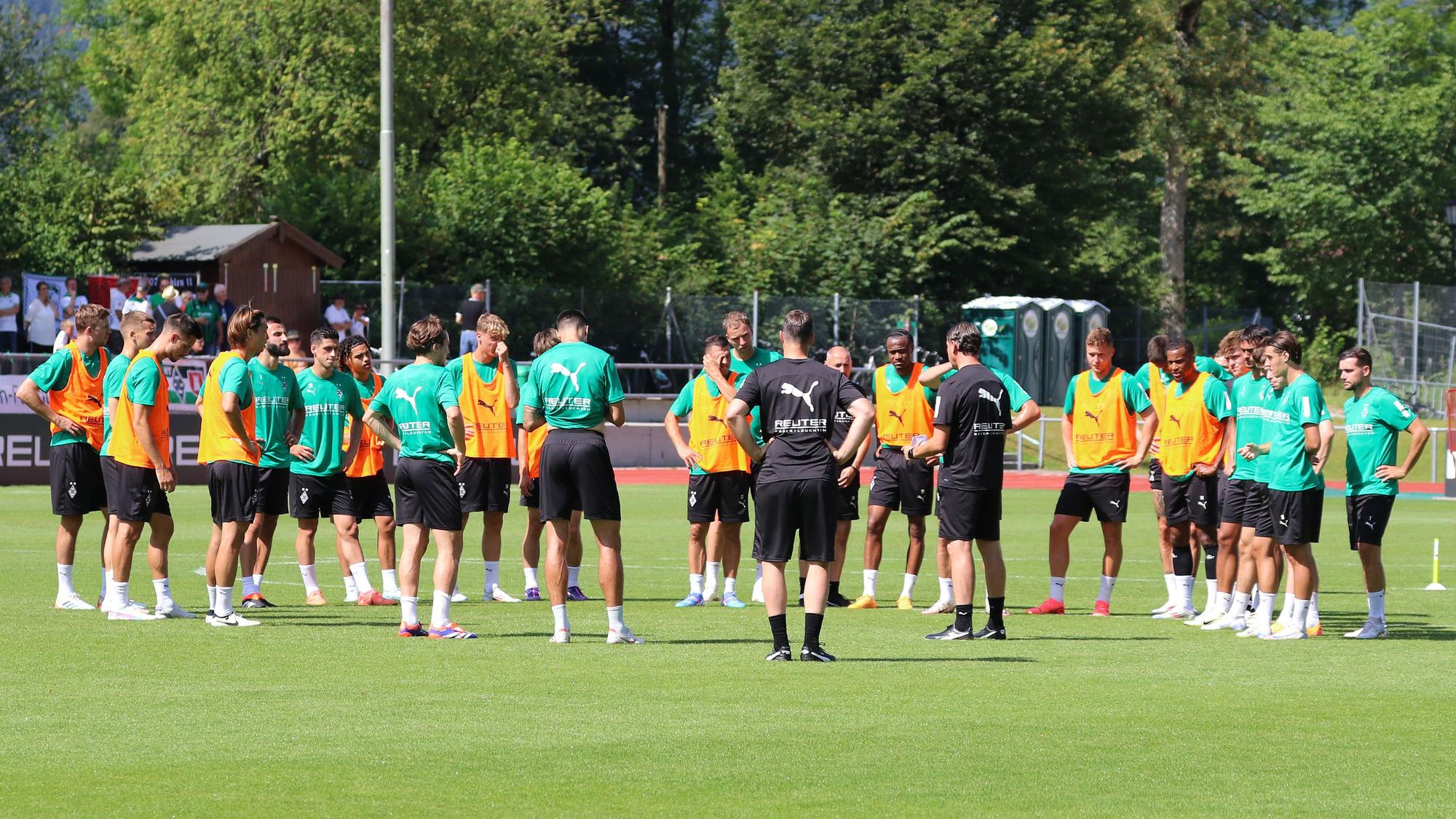 Die Spieler und Trainer von Borussia Mönchengladbach stehen auf dem Trainingsplatz im Kreis zusammen.