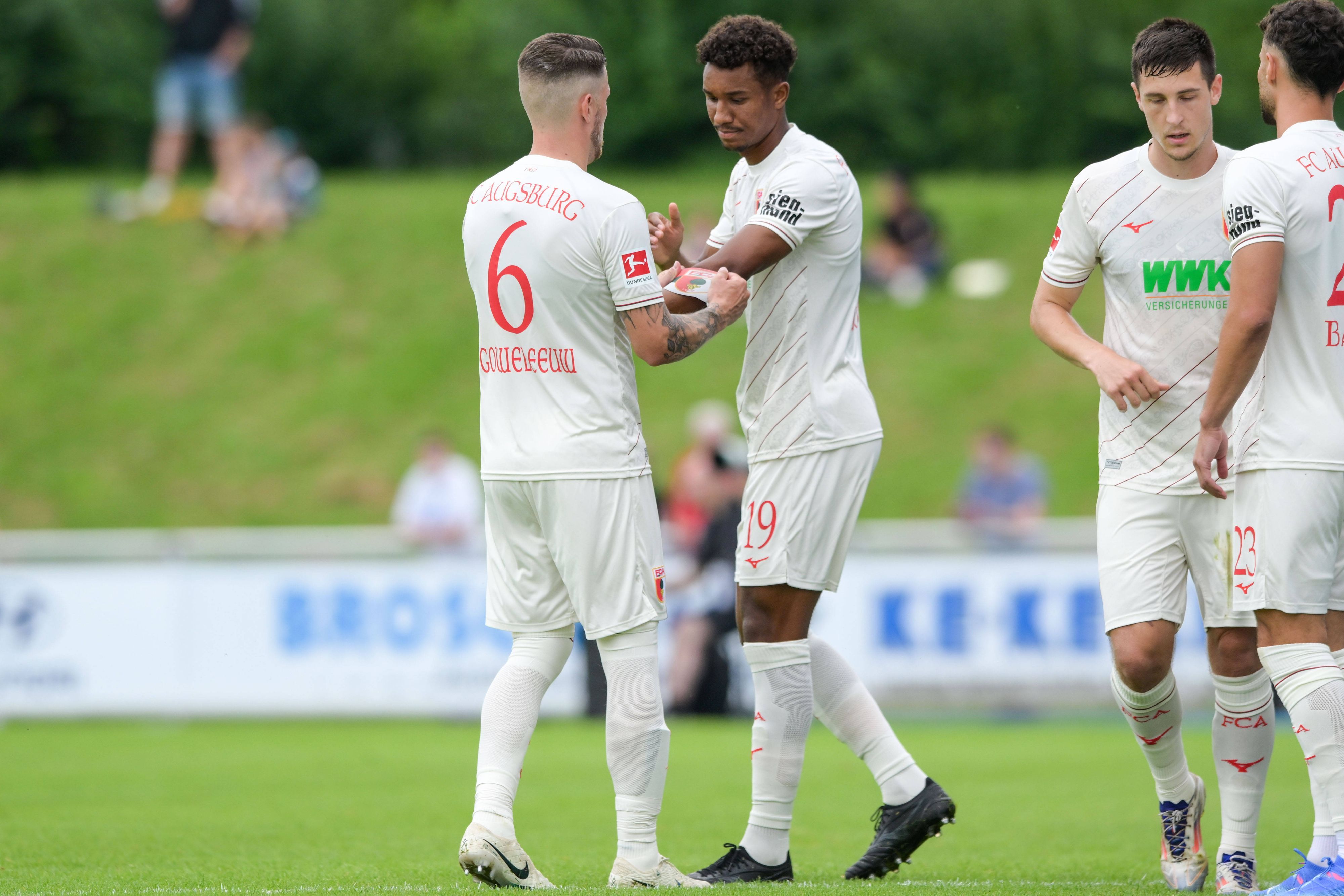 Augsburgs Jeffrey Gouweleeuw übergibt die Kapitänsbinde an seinen Augsburger Teamkollegen Felix Uduokhai.