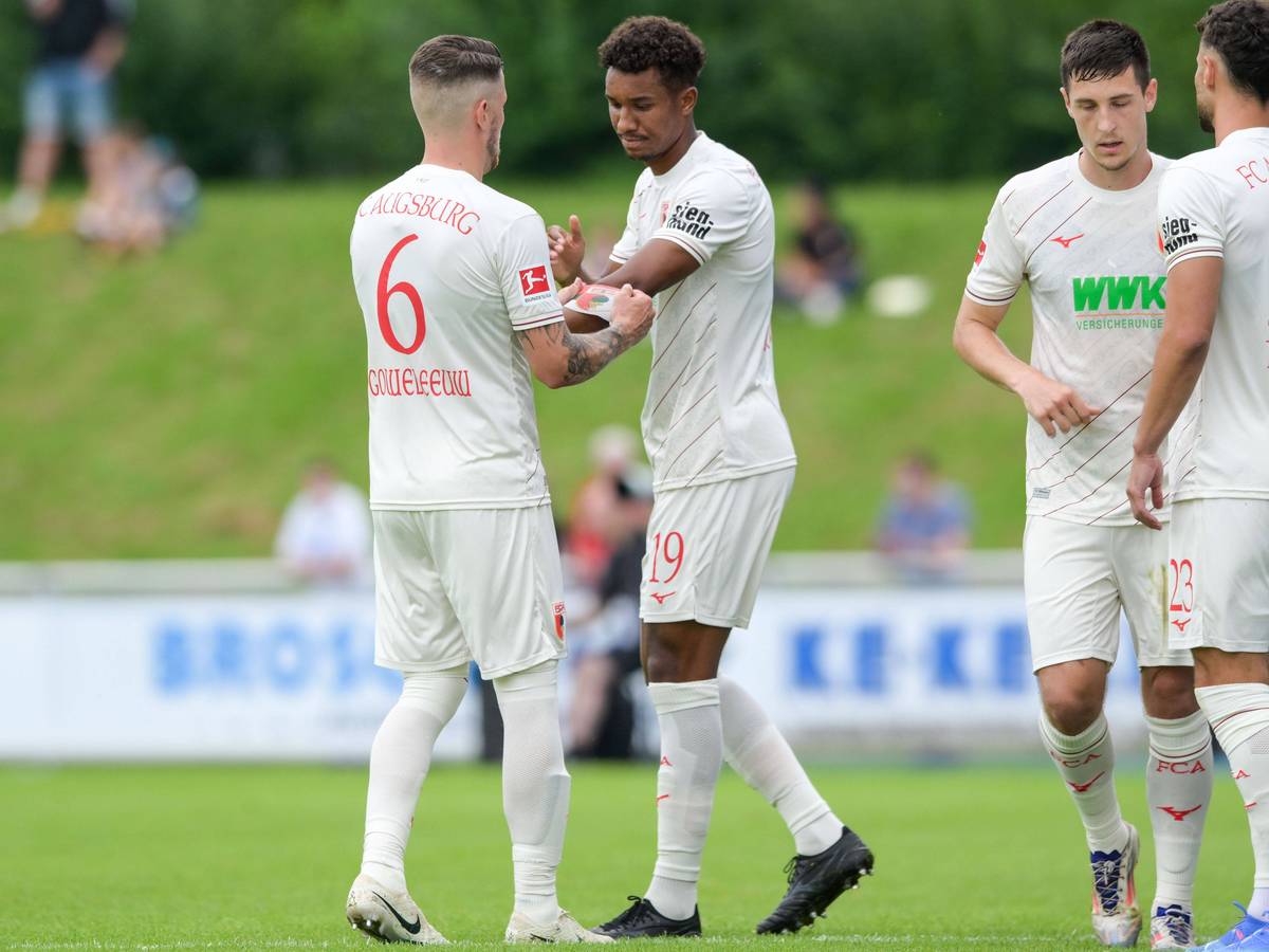 Augsburgs Jeffrey Gouweleeuw übergibt die Kapitänsbinde an seinen Augsburger Teamkollegen Felix Uduokhai.