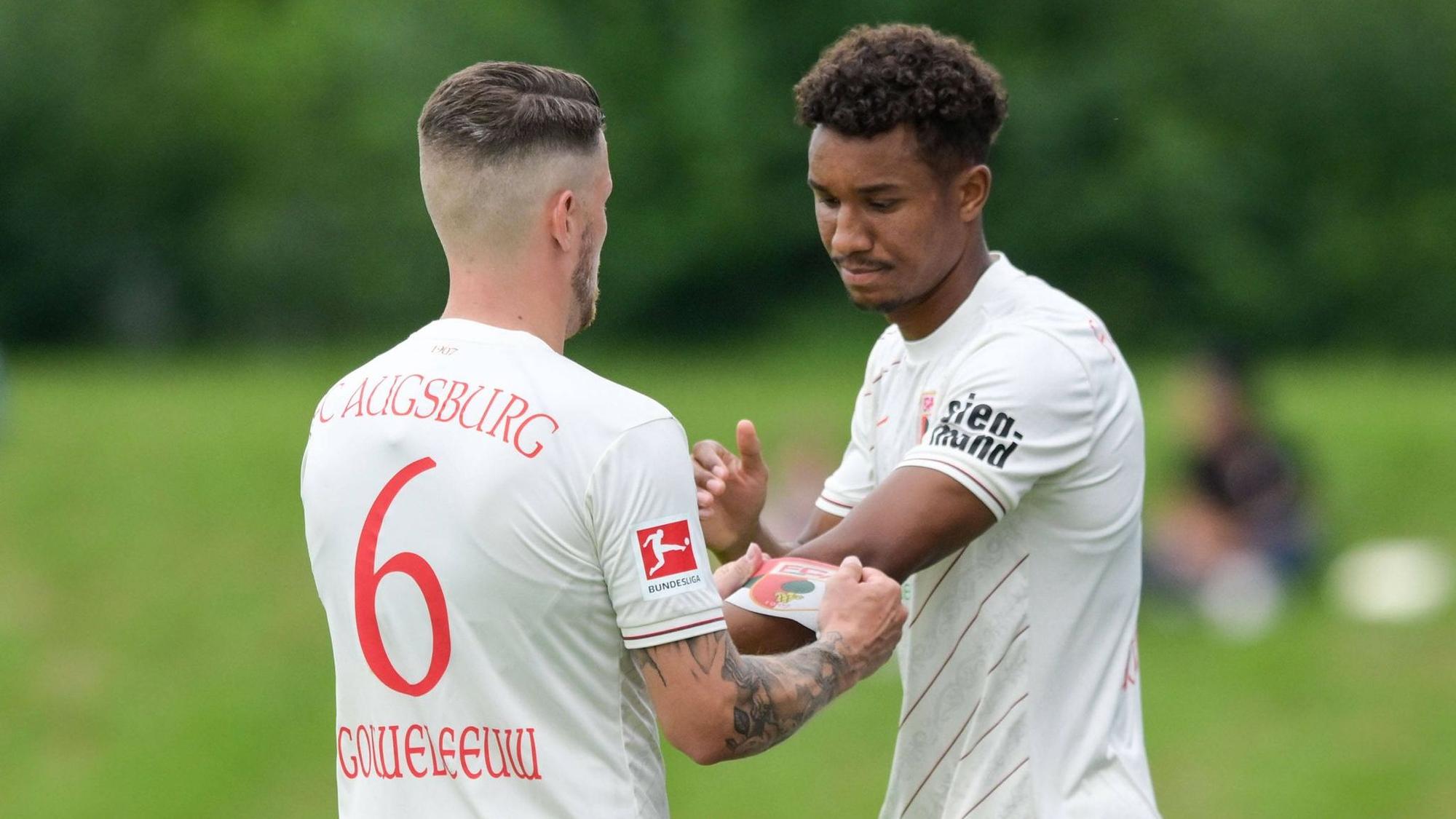 Augsburgs Jeffrey Gouweleeuw übergibt die Kapitänsbinde an seinen Augsburger Teamkollegen Felix Uduokhai.
