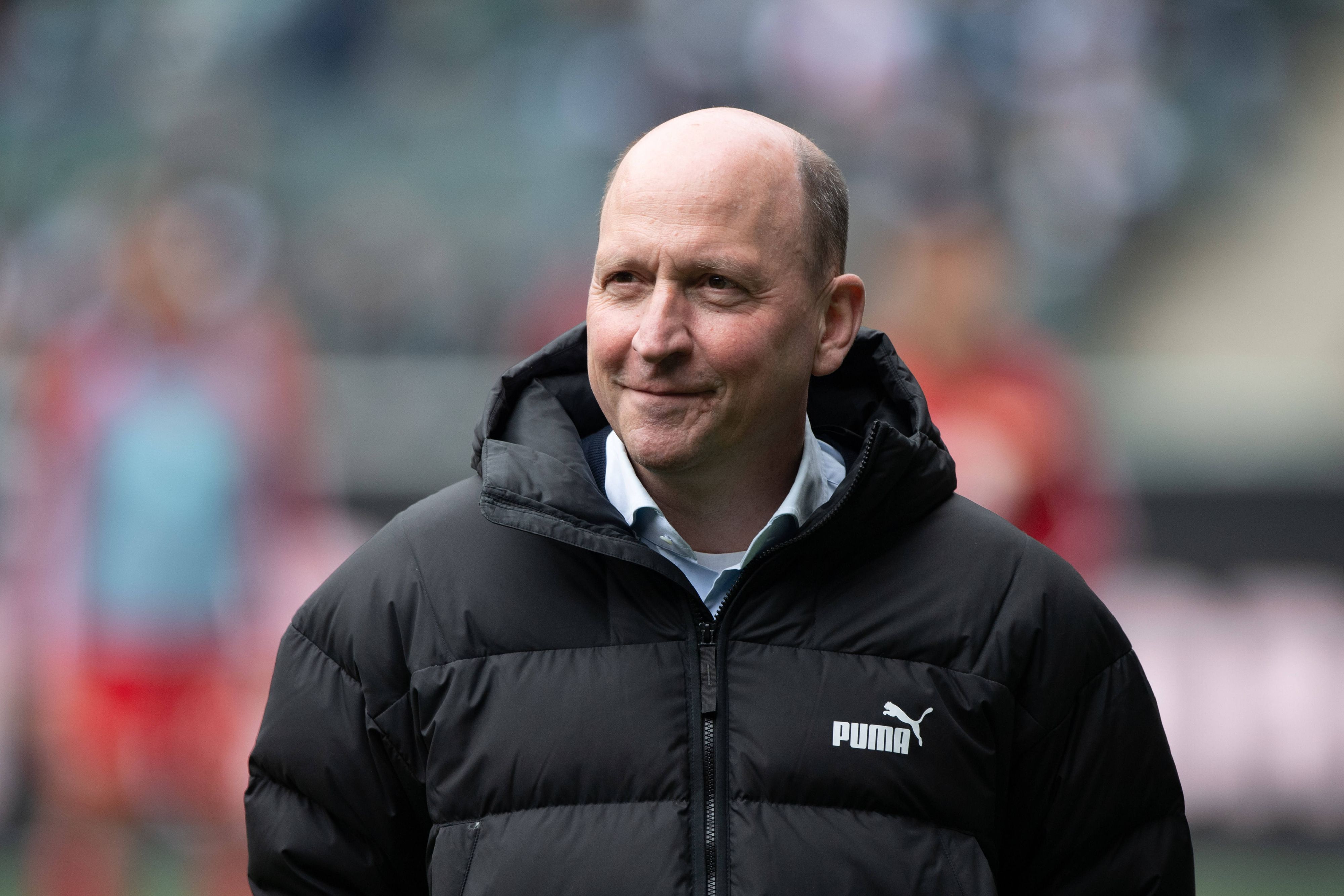 Geschäftsführer Stephan Schippers steht beim Spiel Borussia Mönchengladbach gegen Union Berlin im Stadion und lächelt.