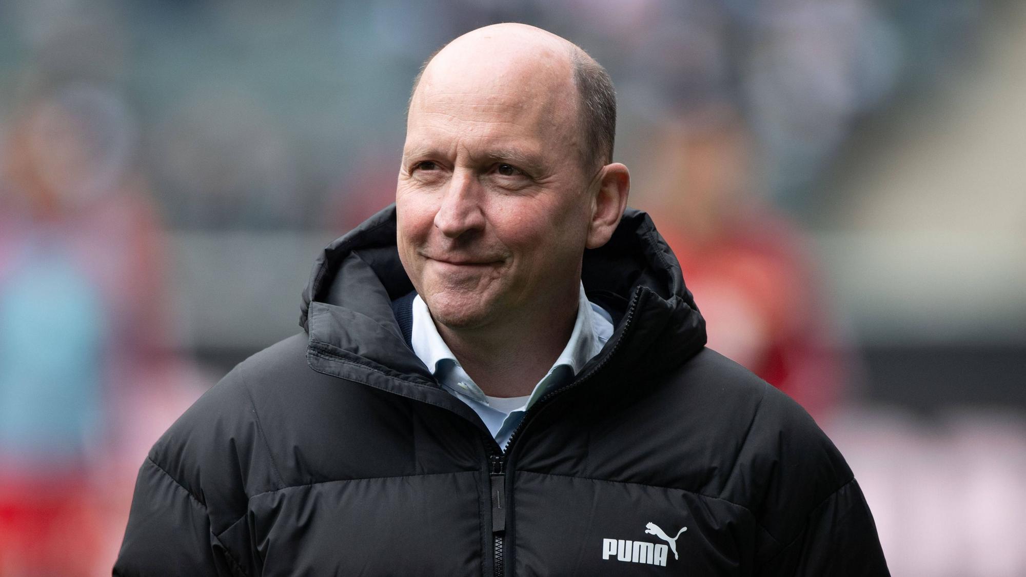 Geschäftsführer Stephan Schippers steht beim Spiel Borussia Mönchengladbach gegen Union Berlin im Stadion und lächelt.