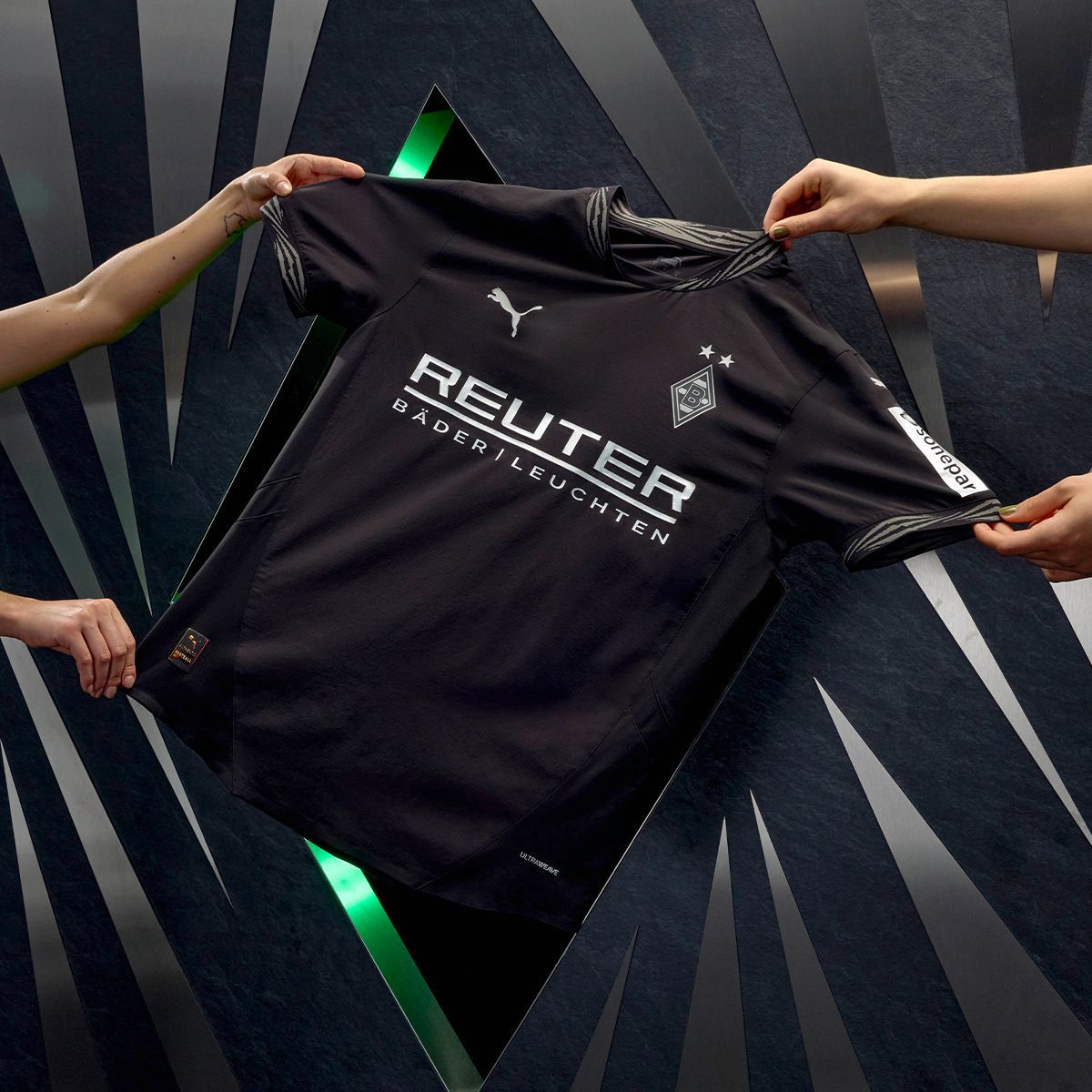 Vier Hände präsentieren das neue Ausweich-Trikot von Borussia Mönchengladbach.