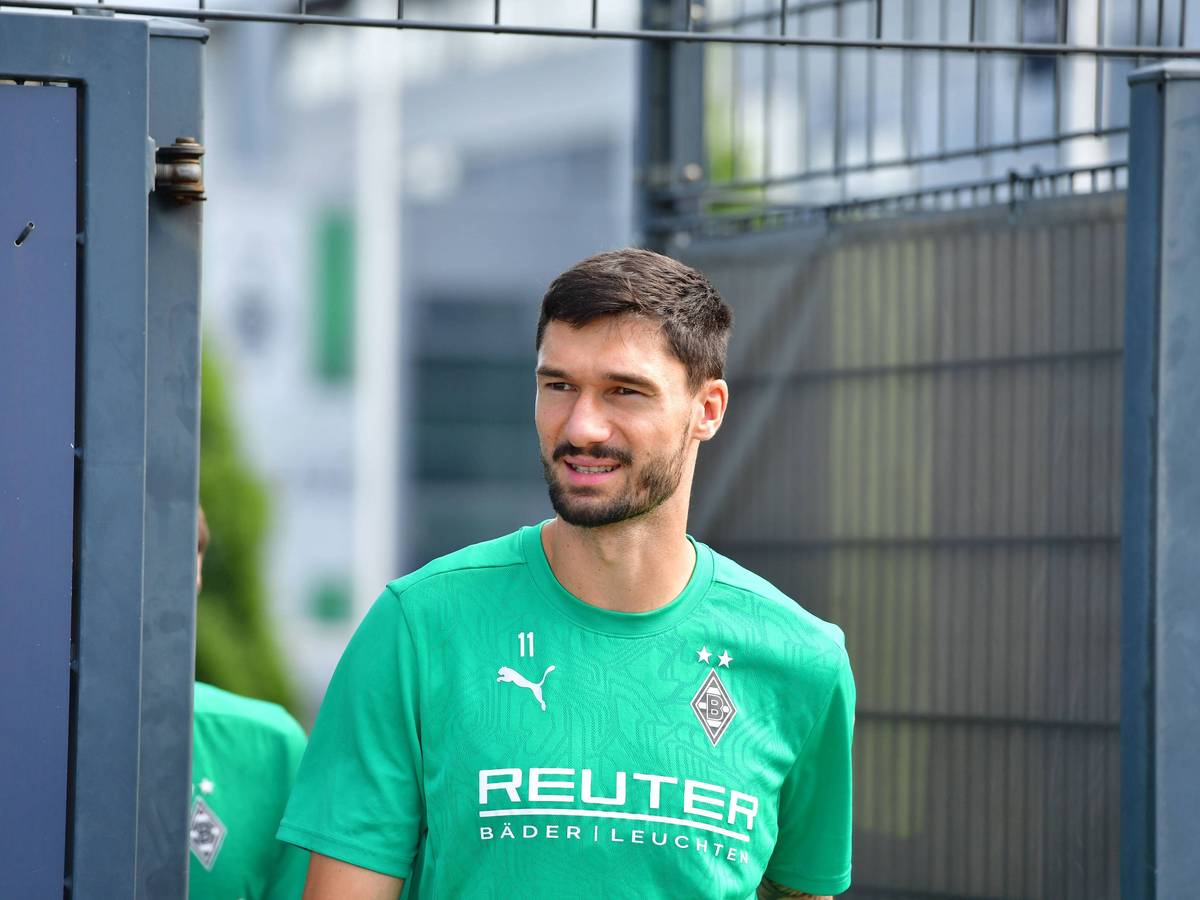 Borussia Mönchengladbachs Tim Kleindienst läuft auf den Trainingsplatz und lächelt in die Kamera.