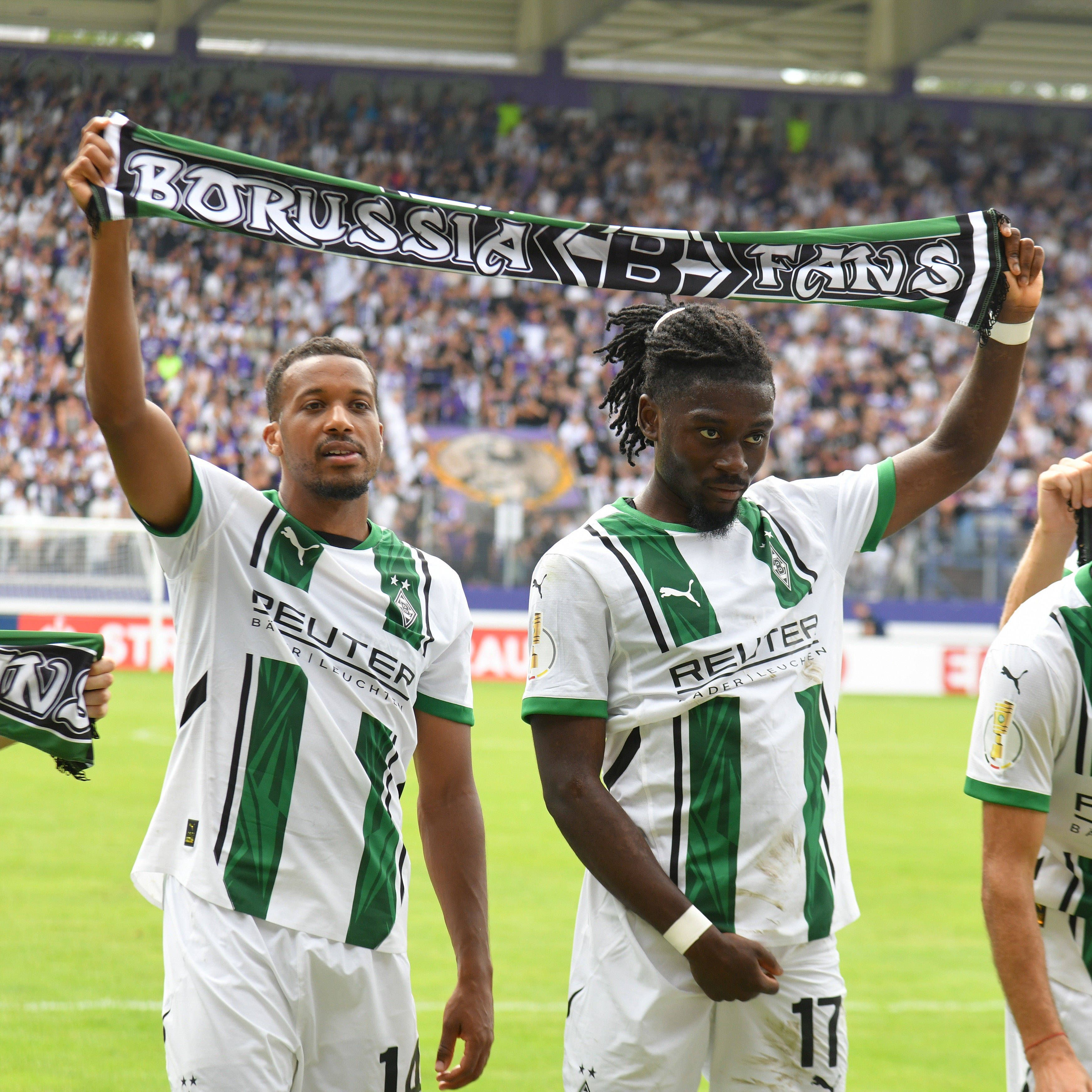 Alassane Plea und Manu Koné halten einen Schal in der Hand.