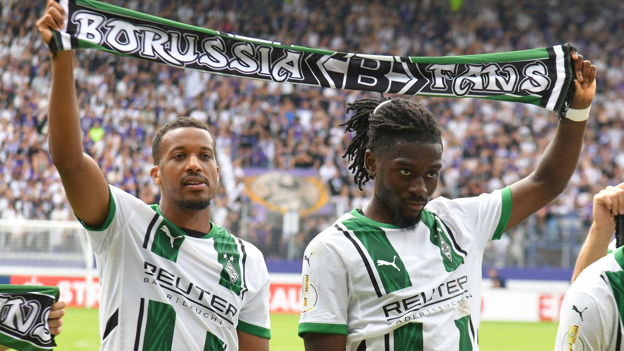 Alassane Plea und Manu Koné halten einen Schal in der Hand.