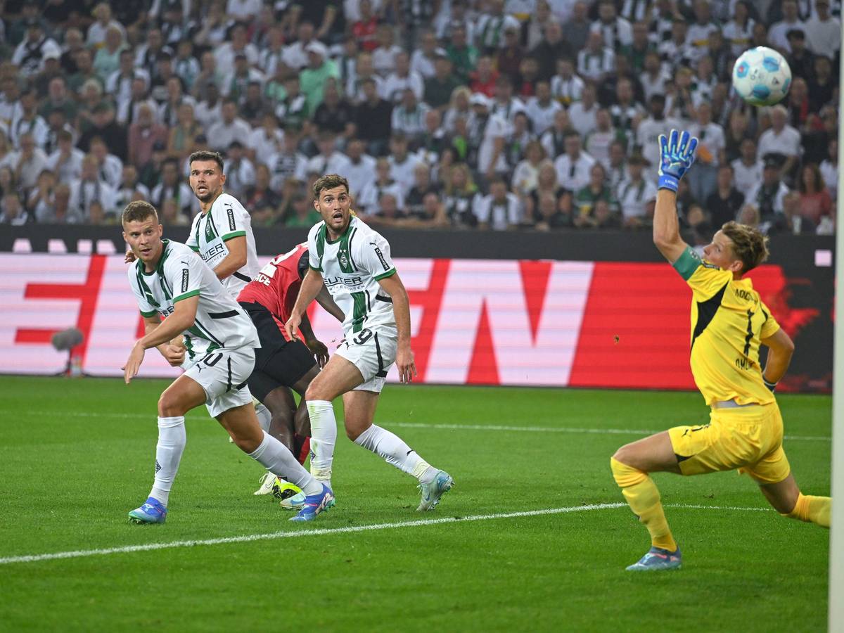 Leverkusens Victor Boniface schießt, die Gladbacher Nico Elvedi, Kevin Stöger und Joe Scally schauen dem Ball bhinterher.