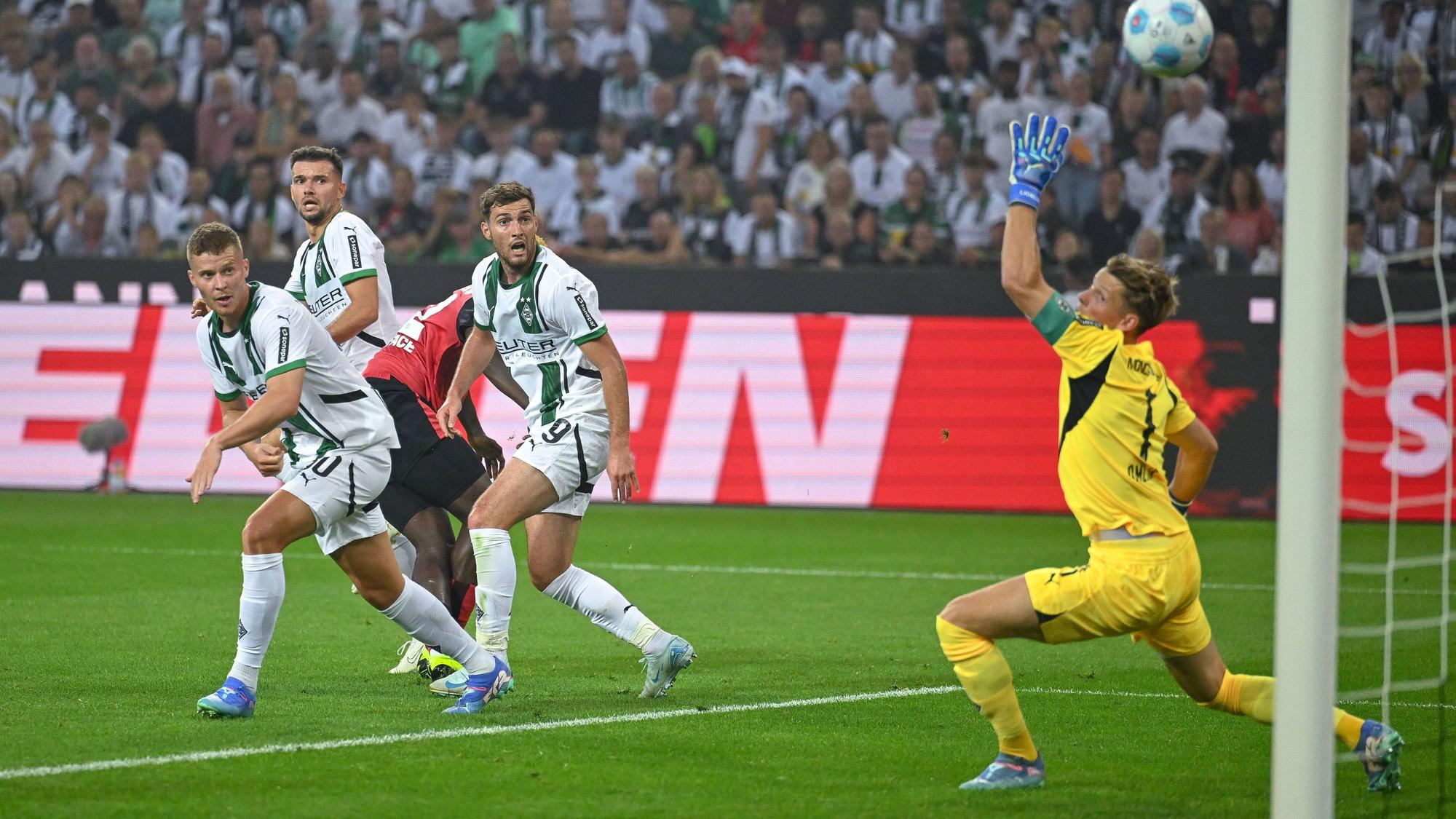 Leverkusens Victor Boniface schießt, die Gladbacher Nico Elvedi, Kevin Stöger und Joe Scally schauen dem Ball bhinterher.