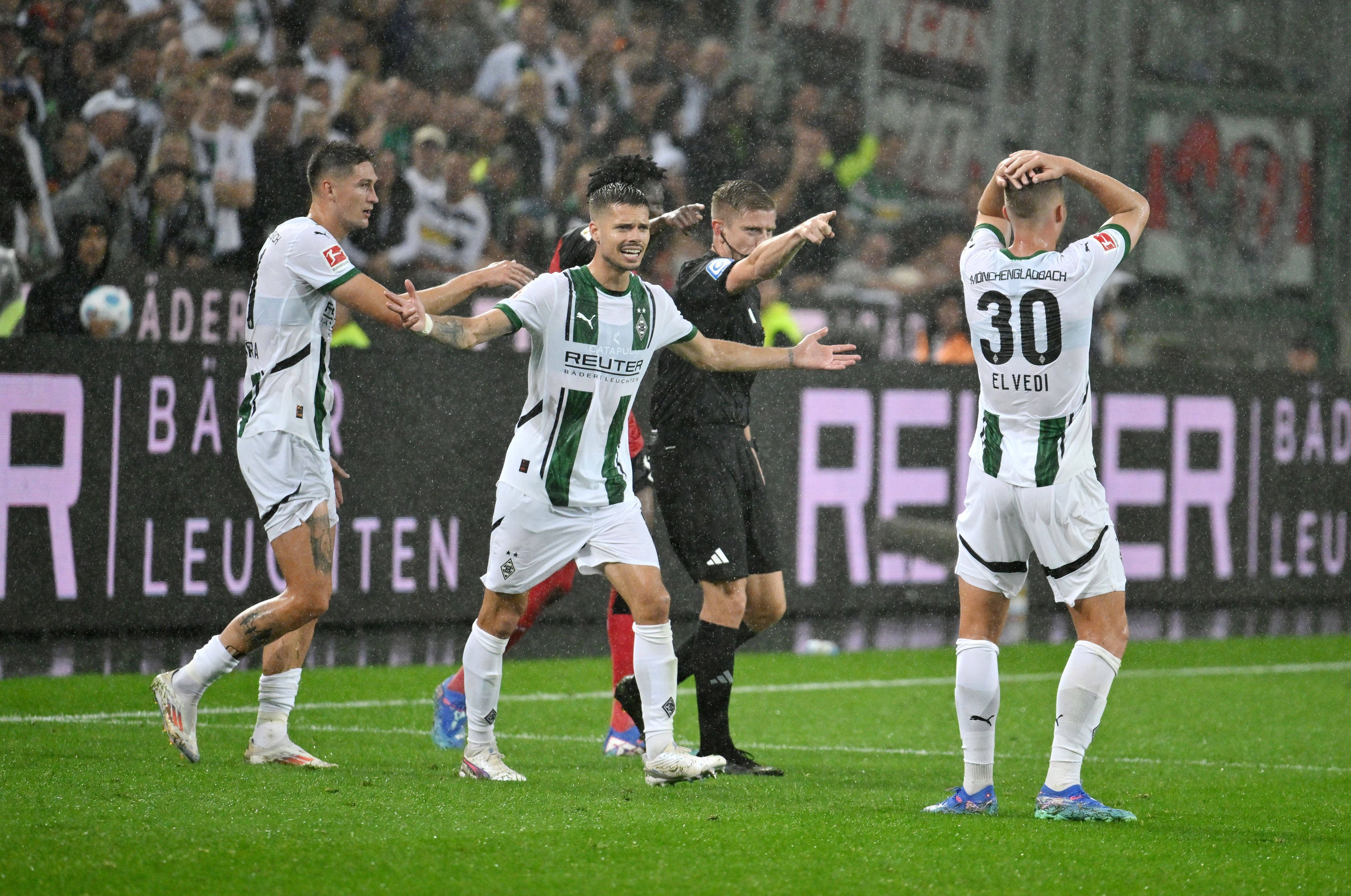Die Gladbach-Profis Tomas Cvancara, Julian Weigl und Nico Elvedi reagieren im Spiel gegen Leverkusen entsetzt auf den Elfmeterpfiff des Schiedsrichters Robert Schröder.