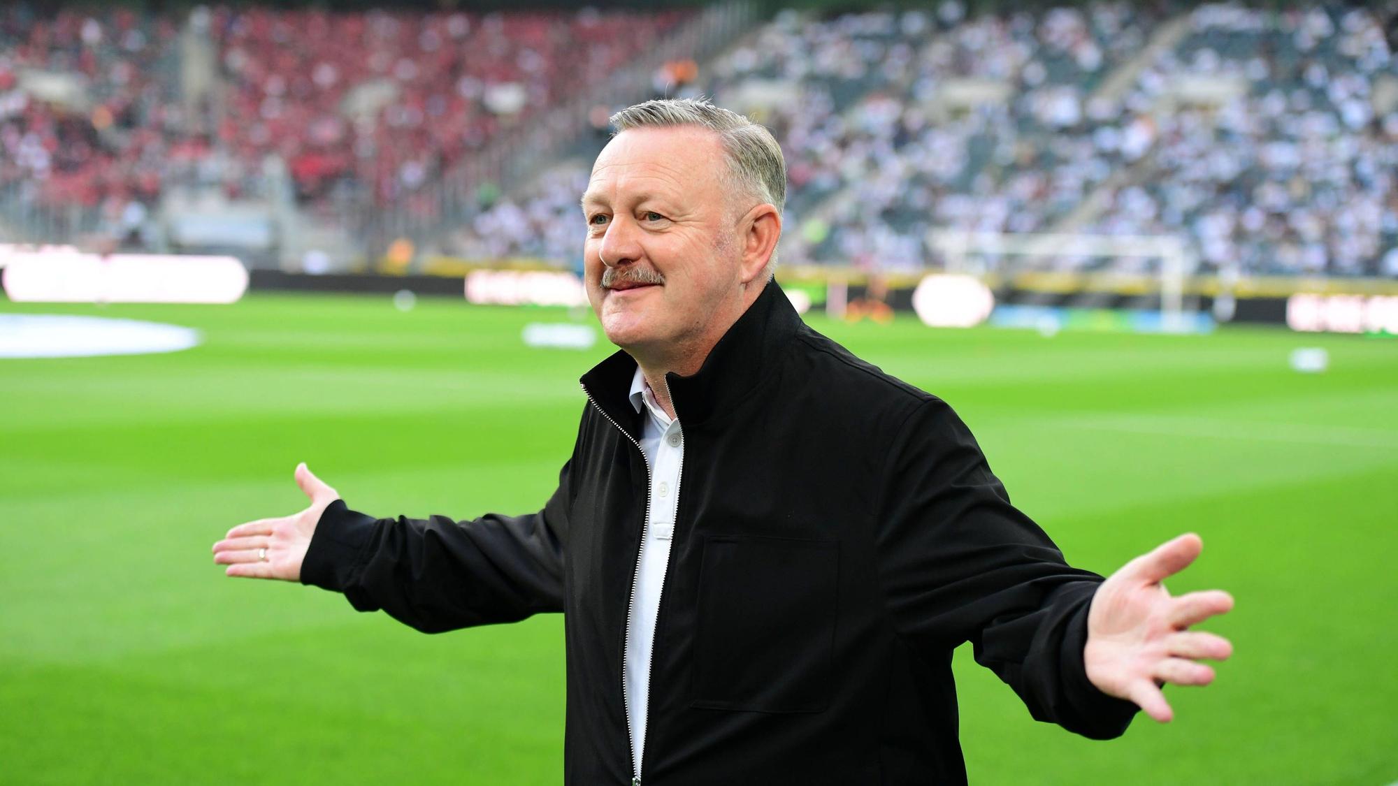 Roland Virkus streckt seine Arme aus und lächelt.