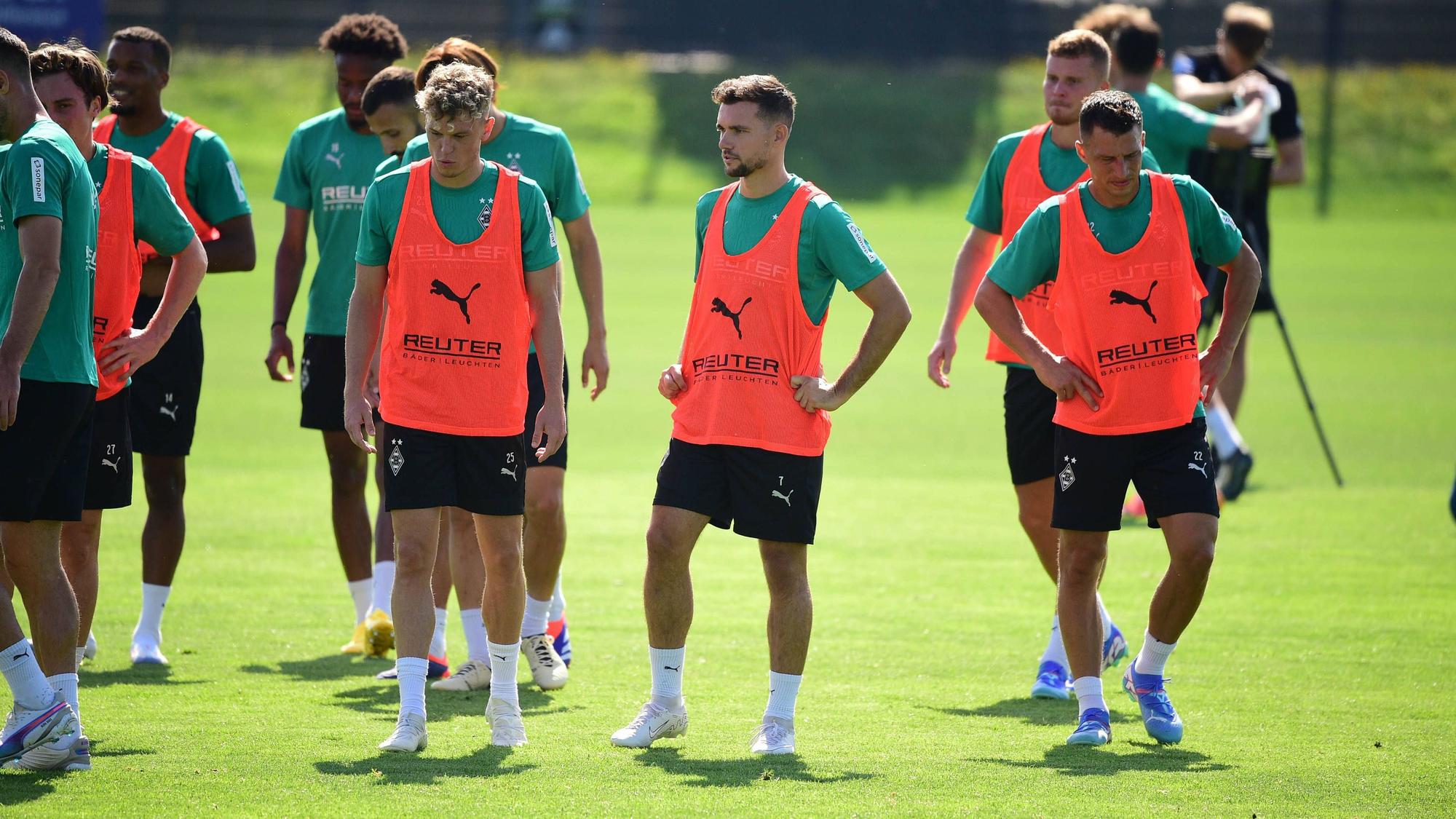 Die Gladbach-Profis Robin Hack, Kevin Stöger und Stefan Lainer stehen nebeneinander auf dem Trainingsplatz und schnaufen durch.