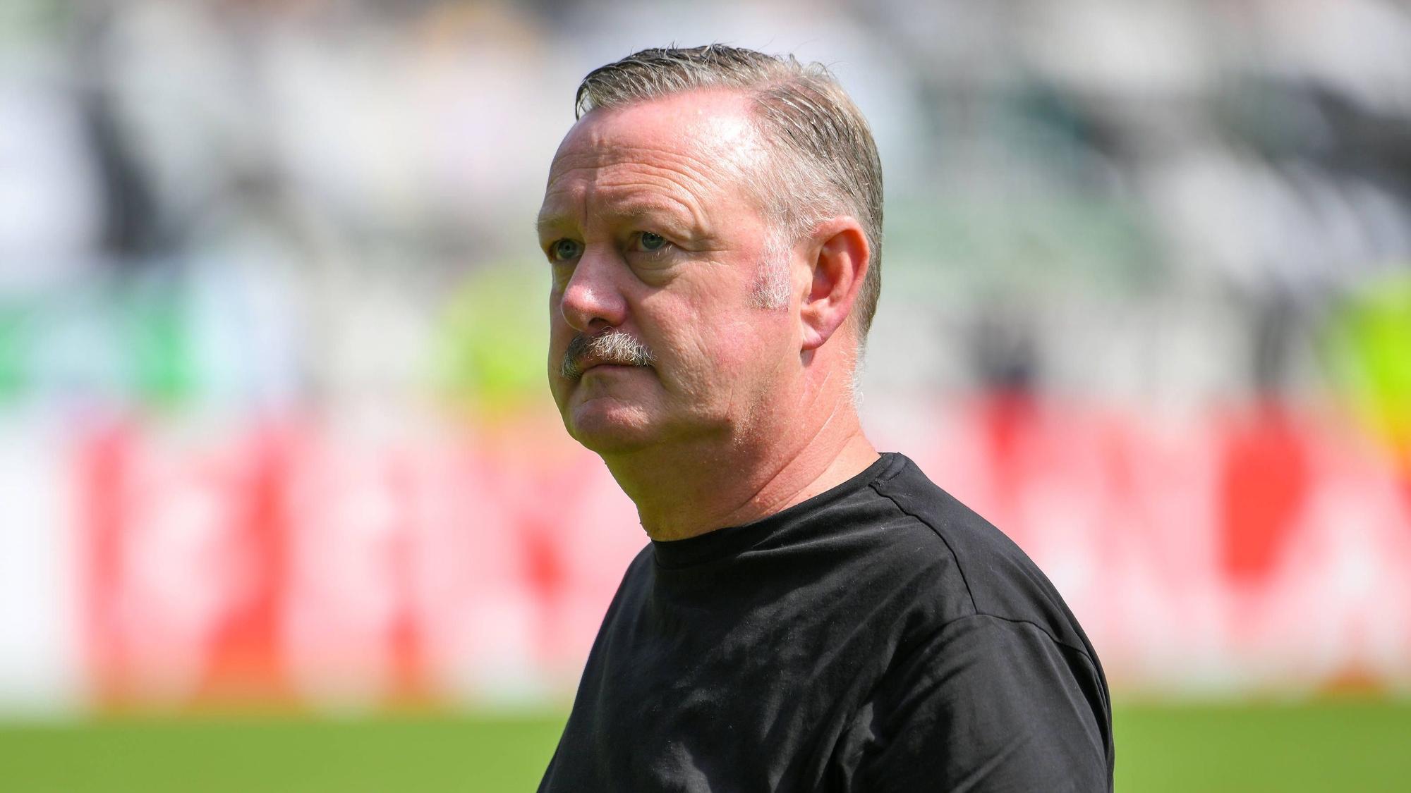 Borussia Mönchengladbachs Sport-Geschäftsführer Roland Virkus steht in Aue auf dem Platz und schaut nachdenklich.