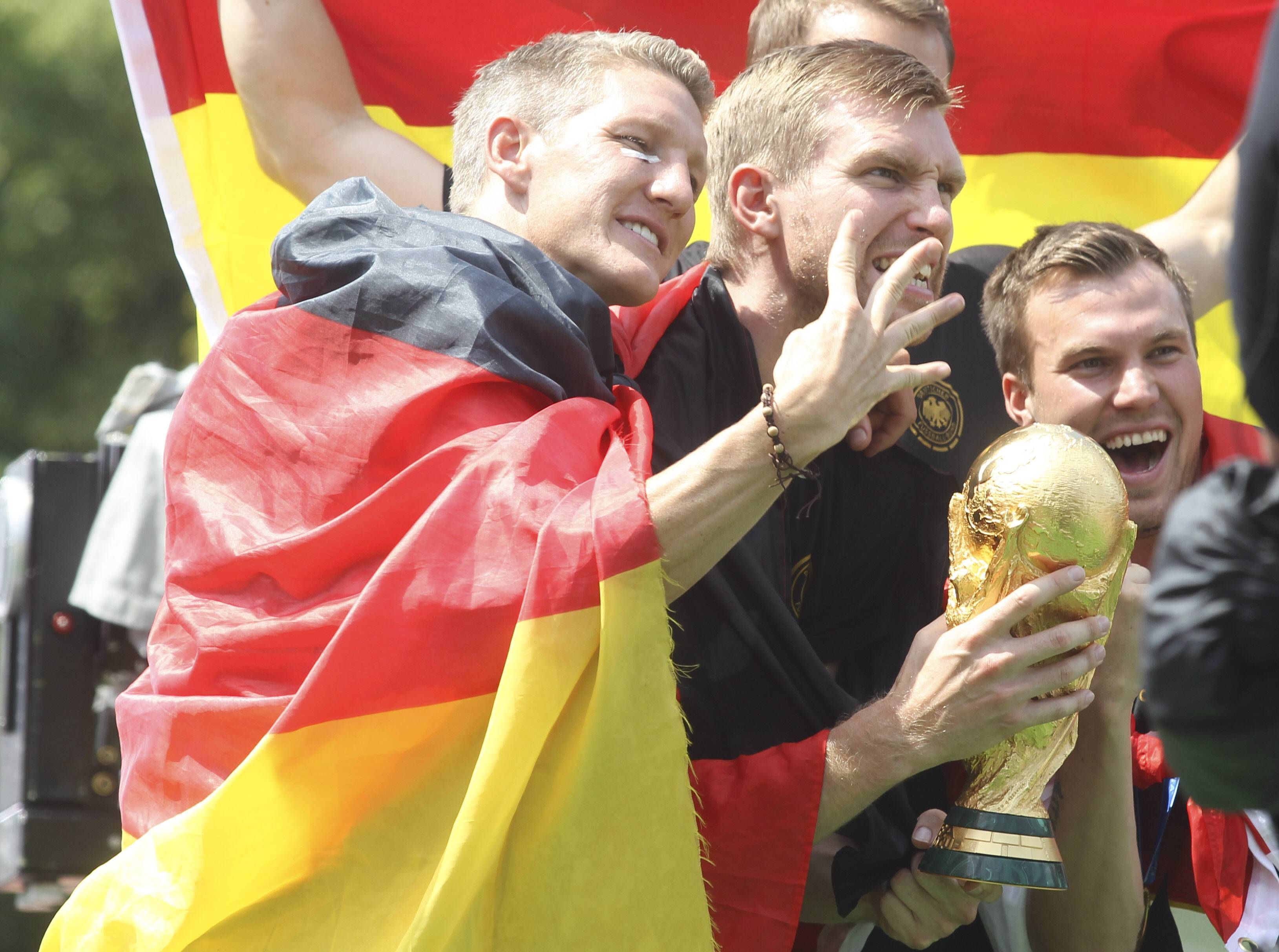 Bastian Schweinsteiger, Per Mertesacker und Kevin Grokreutz juben mit dem Weltmeister-Pokal.