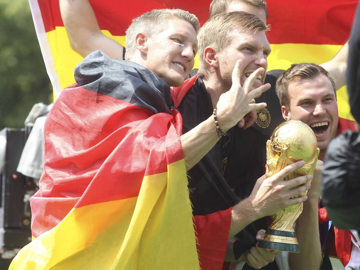Bastian Schweinsteiger, Per Mertesacker und Kevin Grokreutz juben mit dem Weltmeister-Pokal.