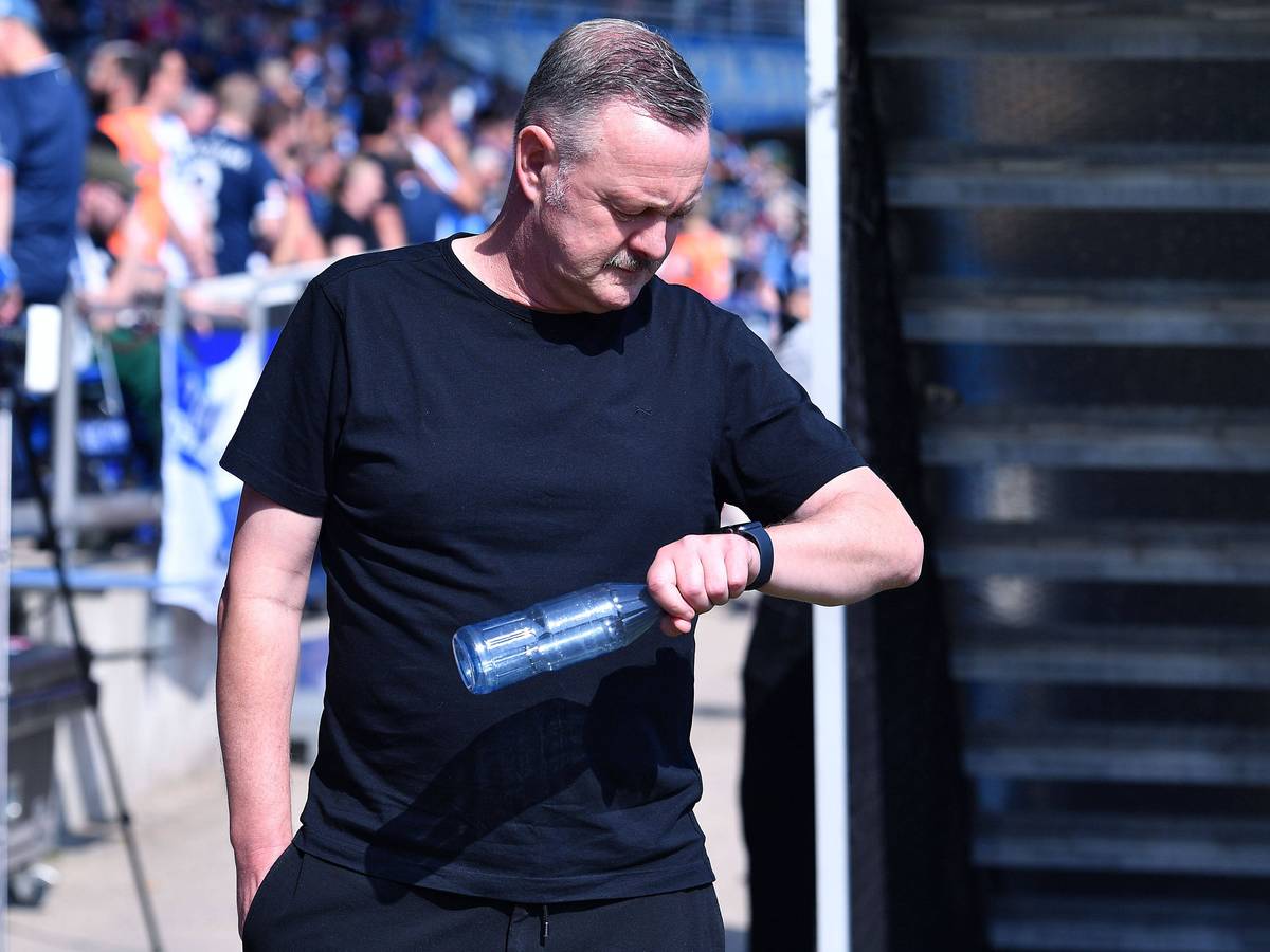 Roland Virkus schaut auf seine Armbanduhr und hält eine Wasserflasche in der Hand.