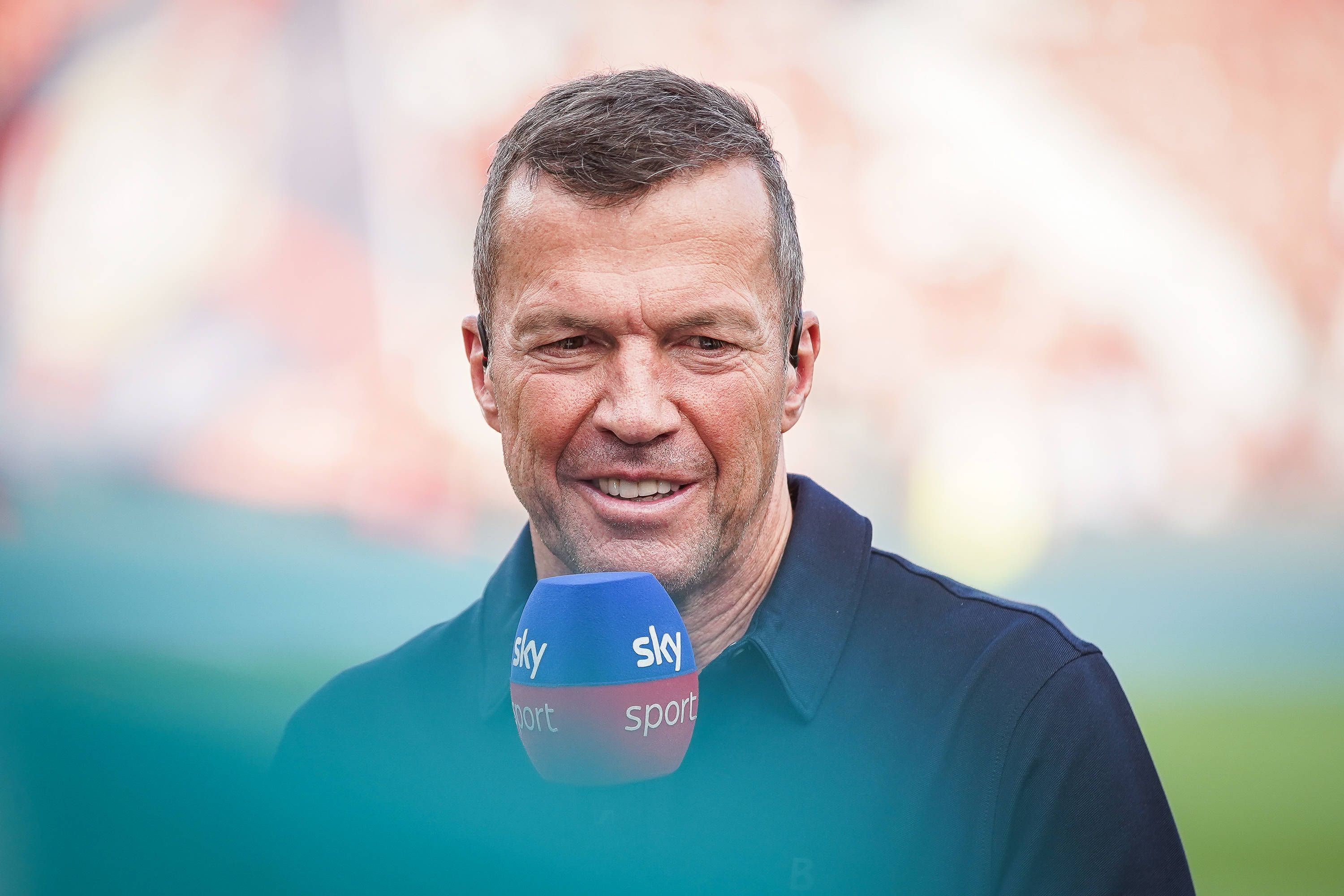 Sky-Experte Lothar Matthäus spricht beim Spiel Bayer Leverkusen gegen RB Leipzig lächelnd ins Mikrofon.