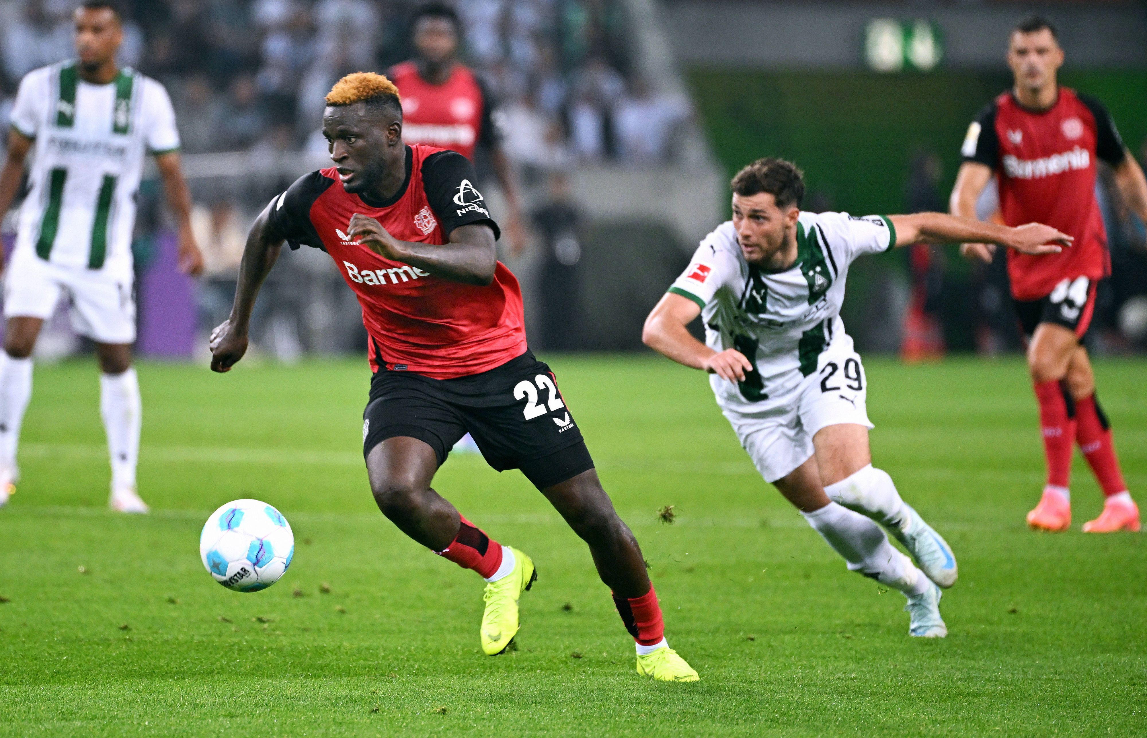 Bayer Leverkusens Victor Boniface führt den Ball, Borussia Mönchengladbachs Joe Scally verfolgt ihn.