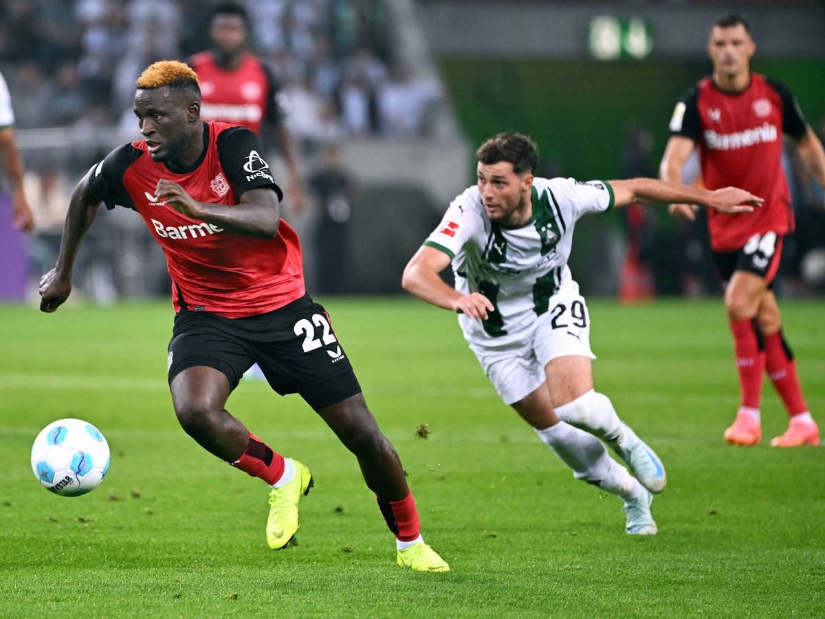 Bayer Leverkusens Victor Boniface führt den Ball, Borussia Mönchengladbachs Joe Scally verfolgt ihn.