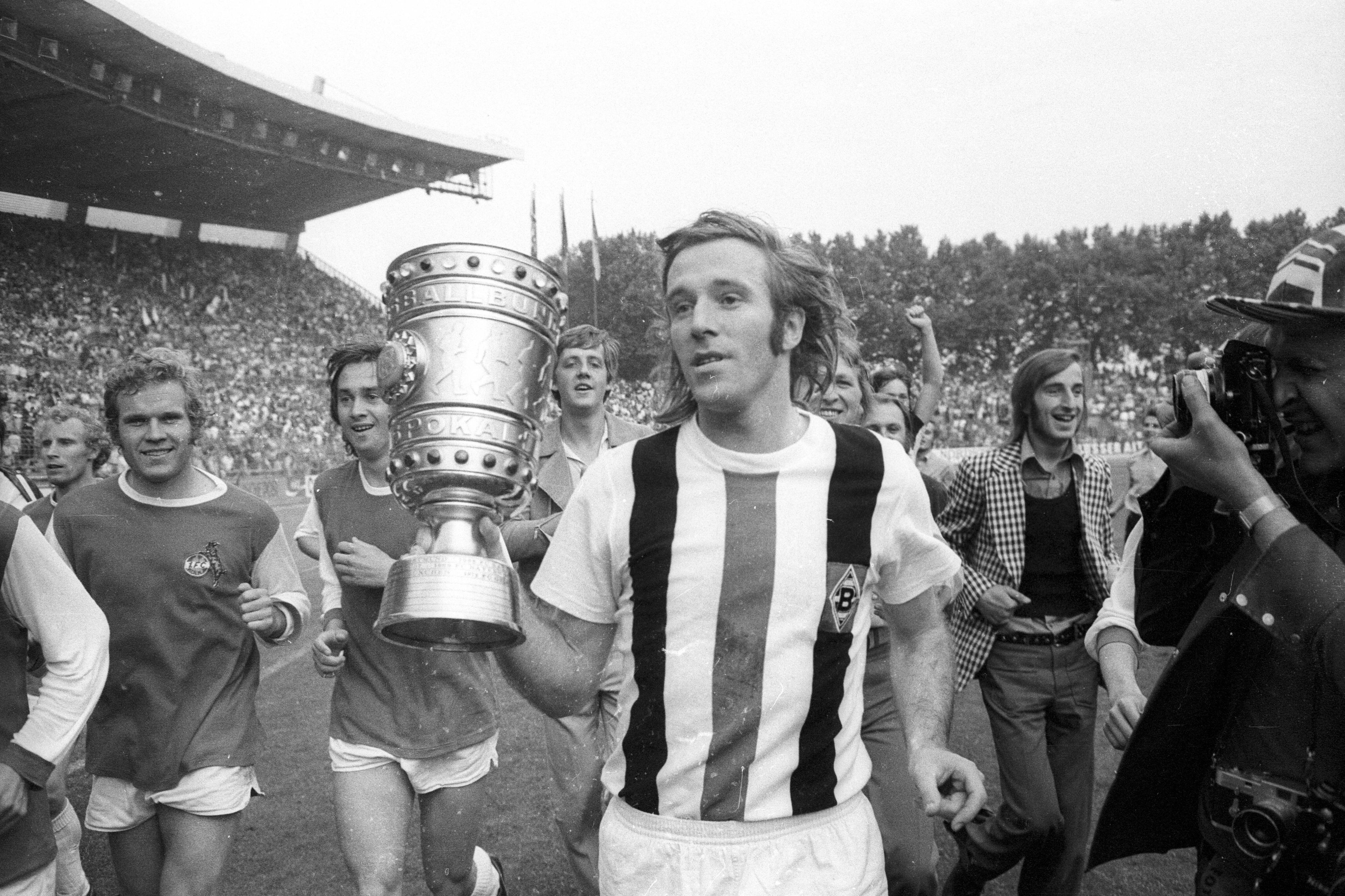 Borussia Mönchengladbachs Siegtorschütze Günter Netzer läuft mit dem DFB-Pokal in der Hand über den Platz.