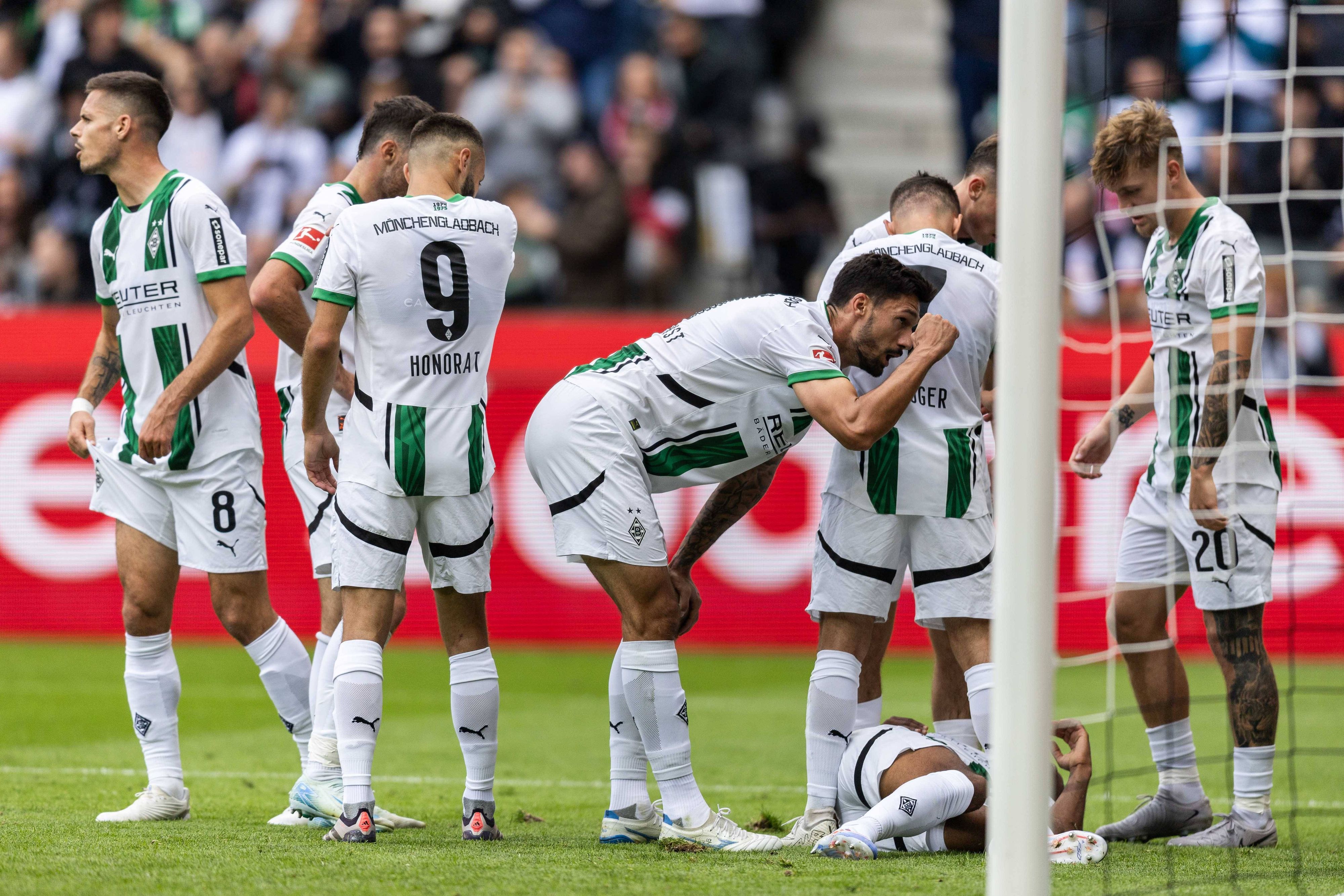 Borussia Mönchengladbachs Alassane Plea liegt im Bundesliga-Spiel gegen den VfB Stuttgart verletzt am Boden, seine Teamkollegen stehen daneben.