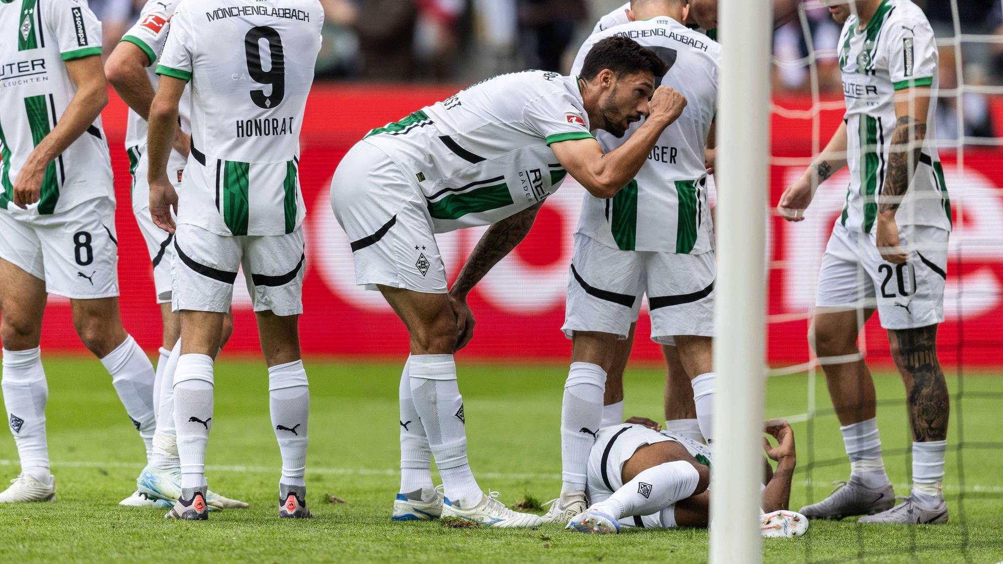 Borussia Mönchengladbachs Alassane Plea liegt im Bundesliga-Spiel gegen den VfB Stuttgart verletzt am Boden, seine Teamkollegen stehen daneben.