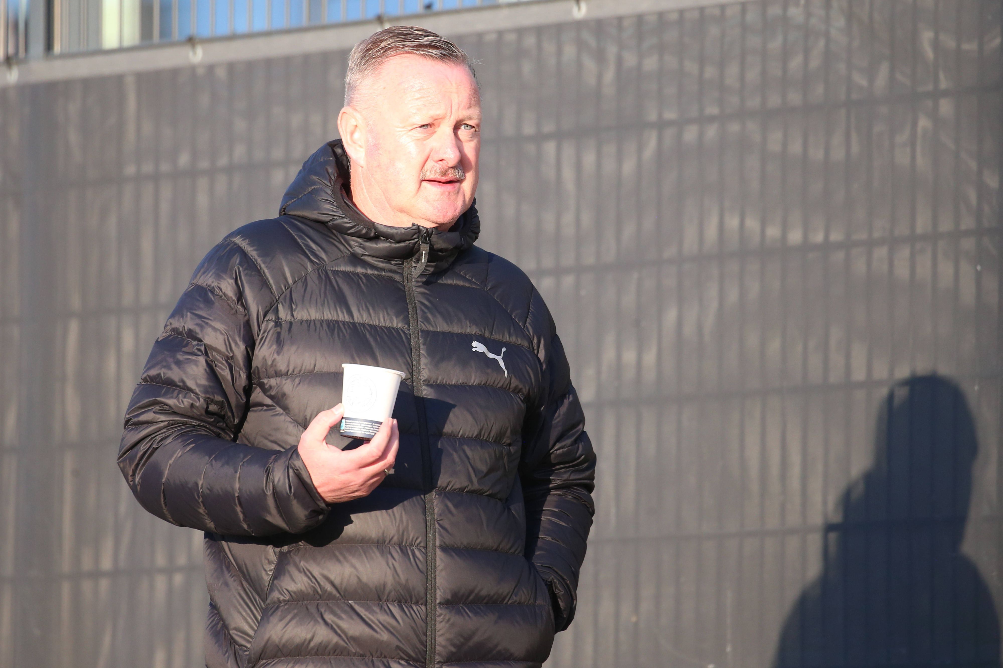 Roland Virkus auf dem Trainingsgelände mit einem Becher Kaffee.