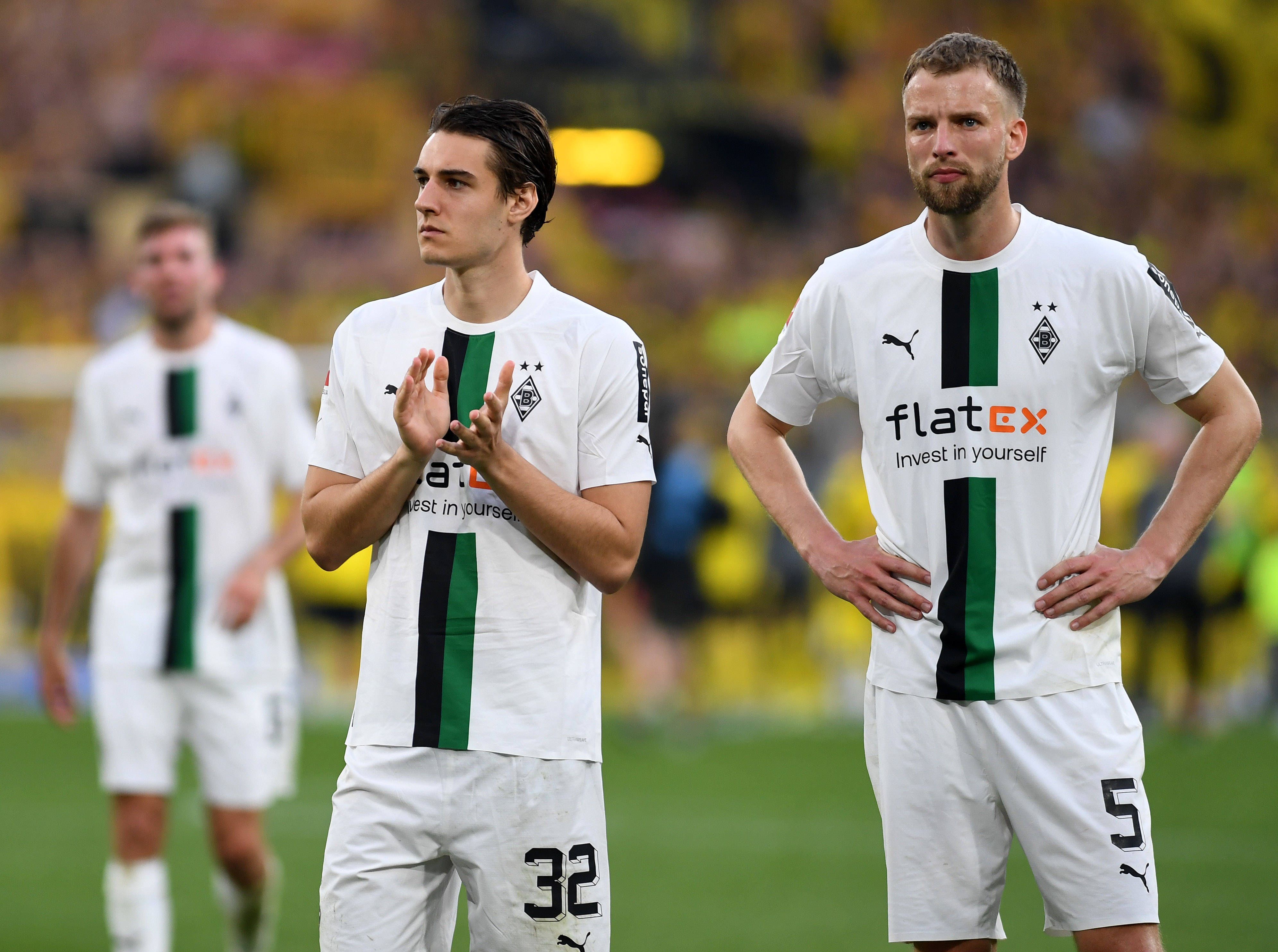 Die Gladbach-Profis Florian Neuhaus und Marvin Friedrich stehen nach dem Spiel bei Borussia Dortmund vor der Fankurve und blicken enttäuscht.