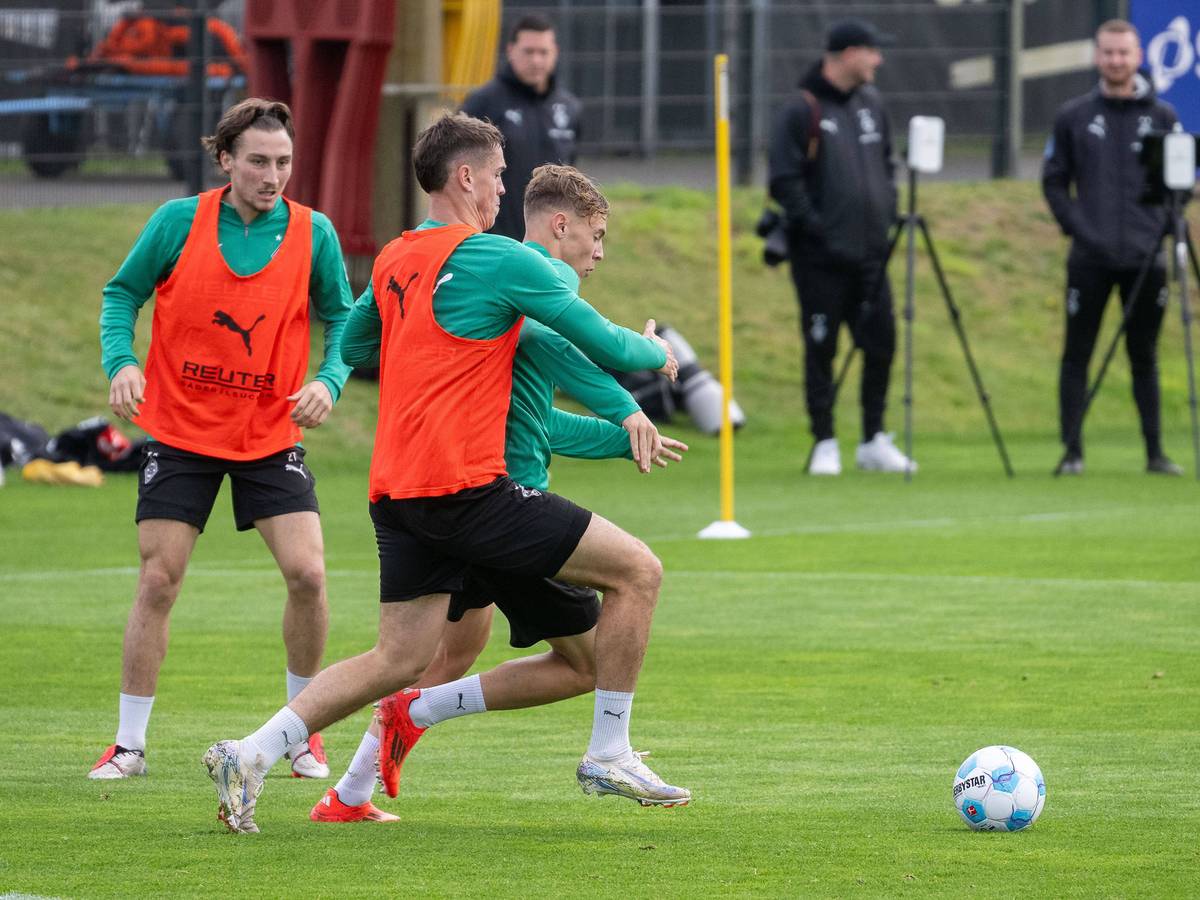 Borussia Mönchengladbachs Philipp Sander kämpft im Training mit Niklas Swider um den Ball. Im Hintergrund beobachtet Rocco Reitz die Szene.