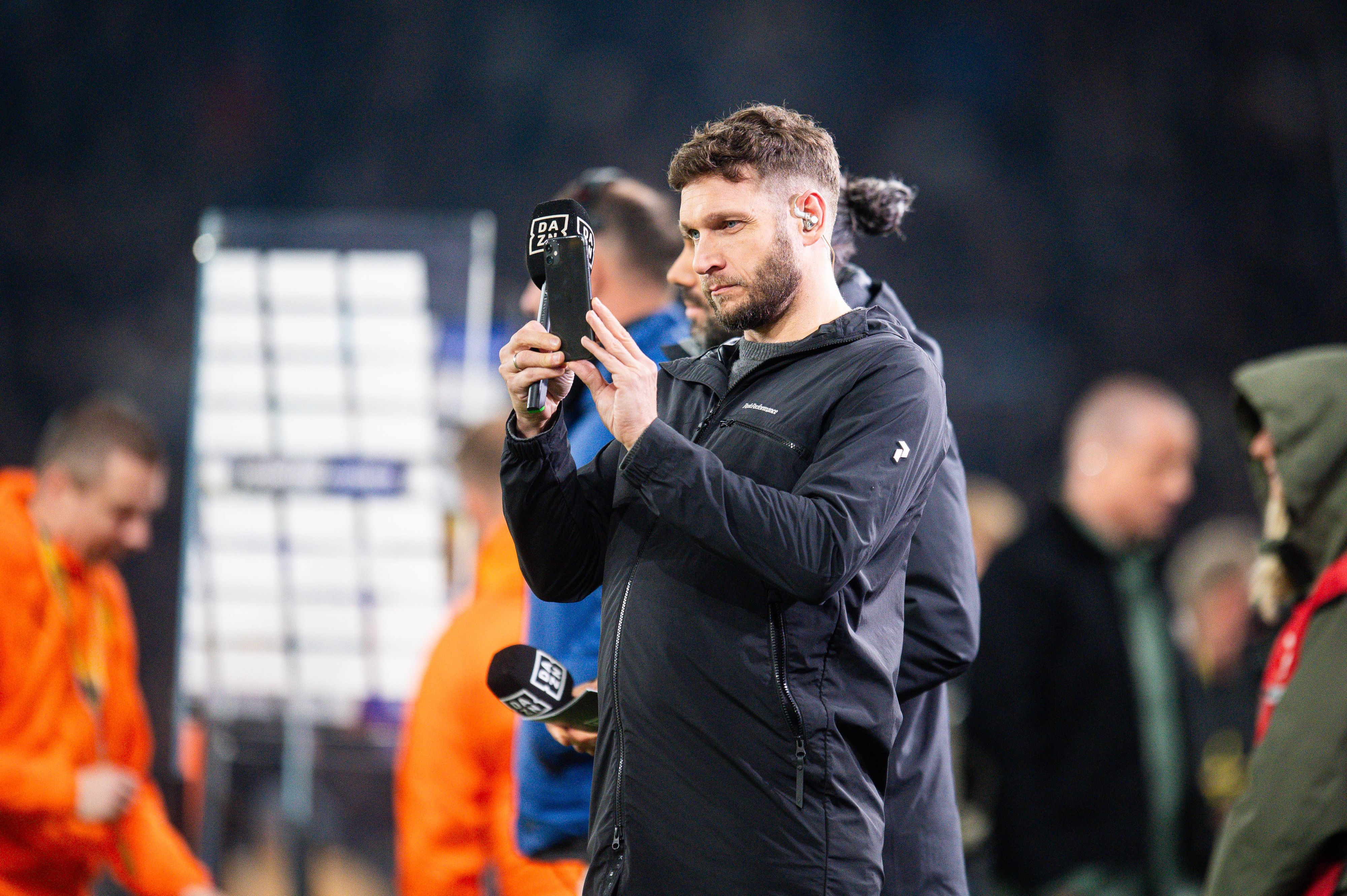 Moritz Volz im Einsatz für DAZN macht ein Foto mit seinem Handy.
