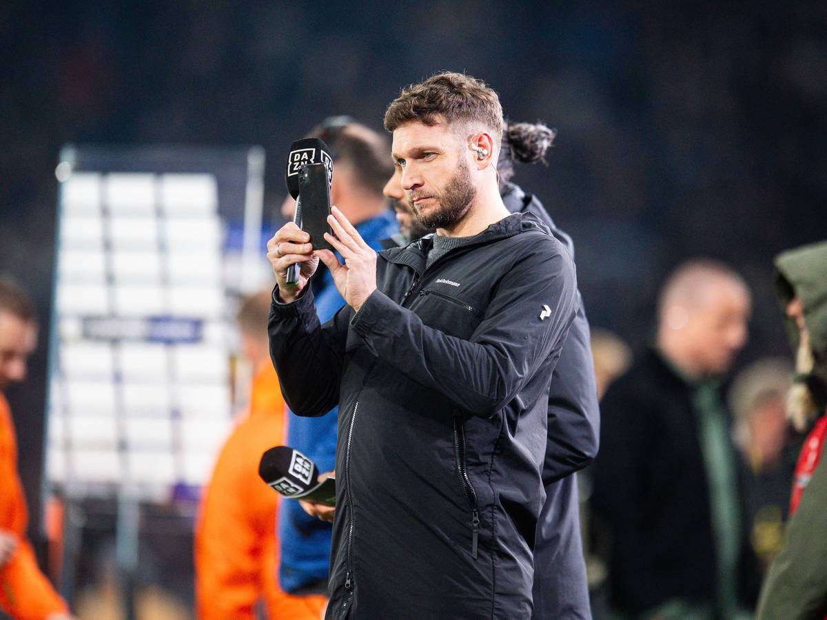 Moritz Volz im Einsatz für DAZN macht ein Foto mit seinem Handy.