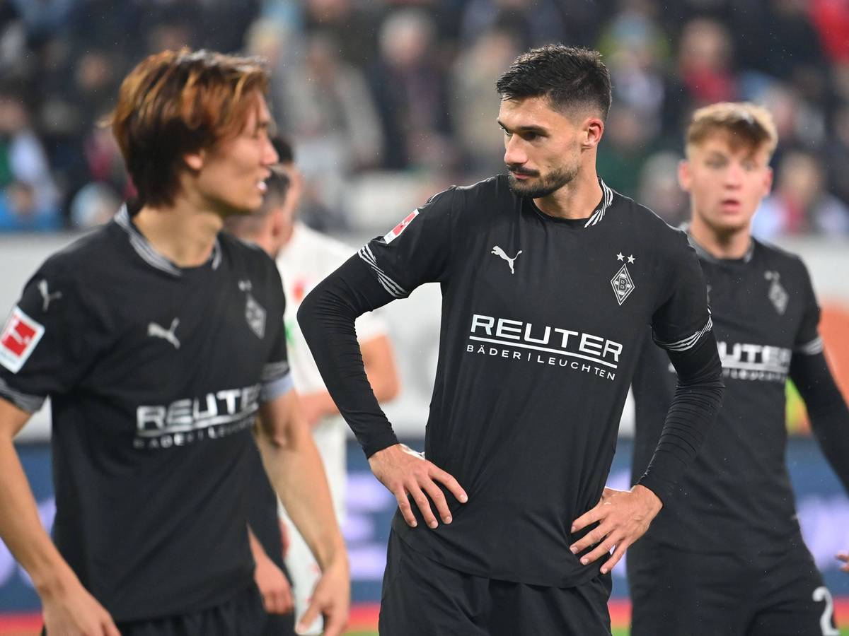 Die Gladbach-Profis Ko Itakura, Tim Kleindienst und Luca Netz stehen nach dem Spiel in Augsburg enttäuscht auf dem Rasen.