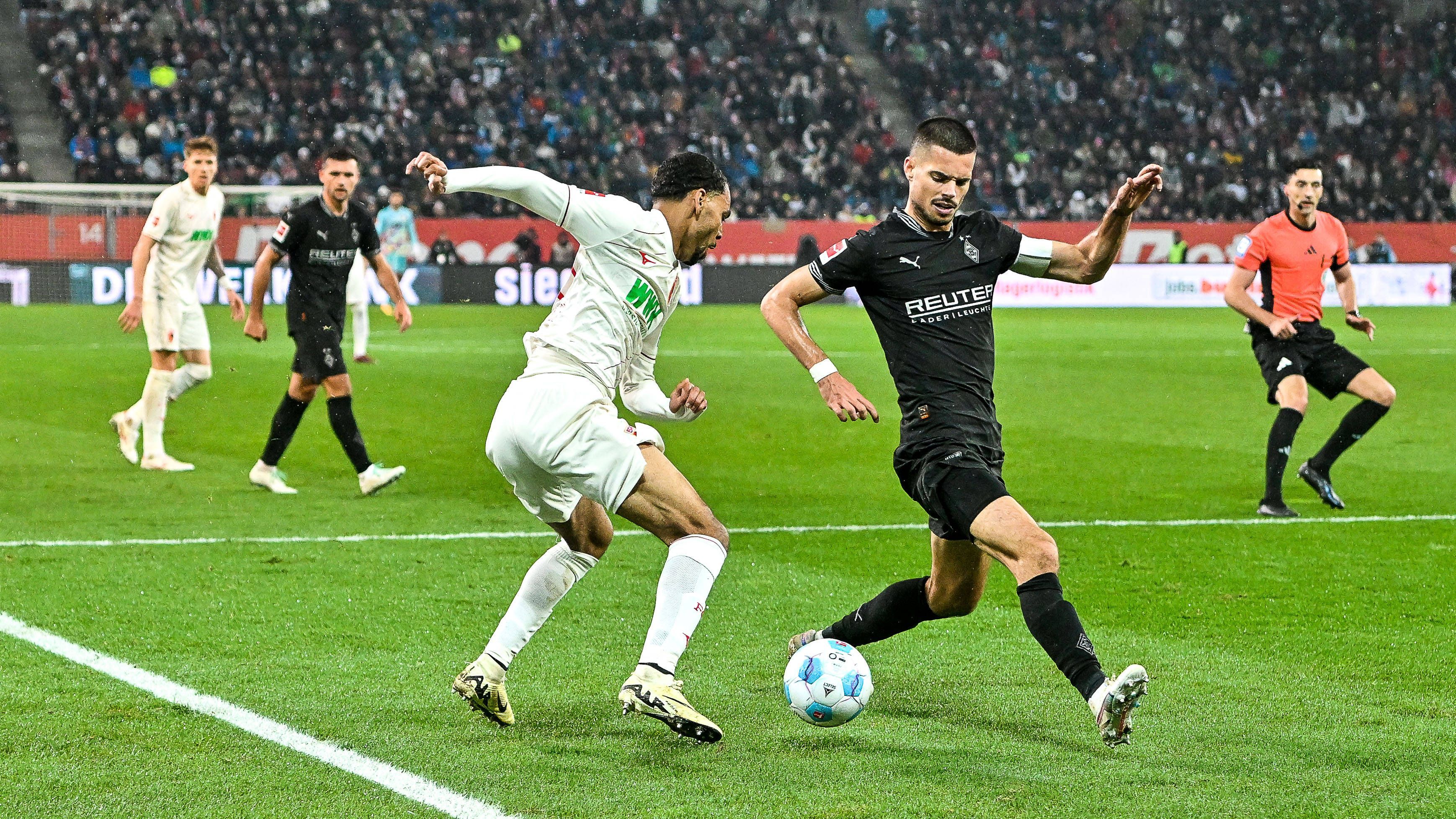 Augsburgs Alexis Claude-Maurice und Borussia Mönchengladbachs Julian Weigl kämpfen um den Ball.