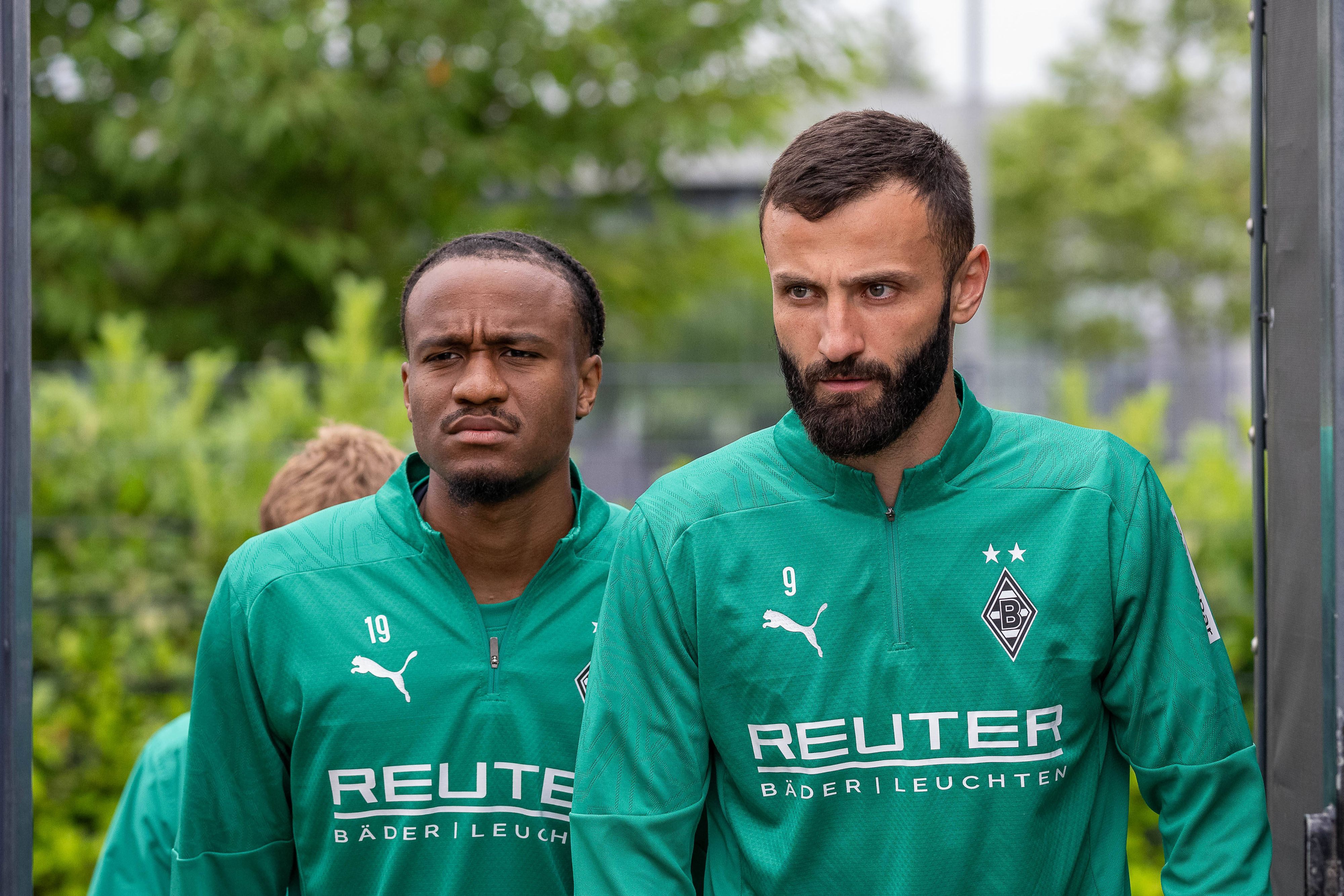 Die Gladbach-Profis Franck Honorat und nathan Ngoumou laufen hintereinander auf den Trainingsplatz.