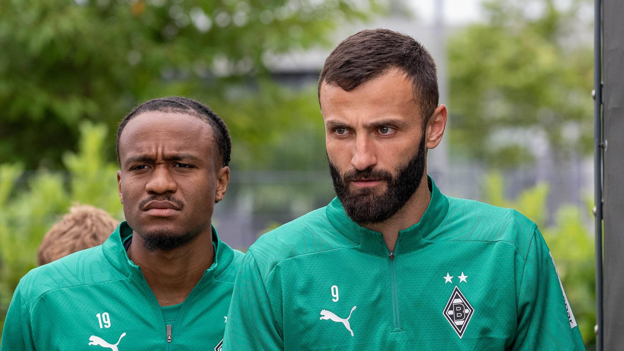 Die Gladbach-Profis Franck Honorat und nathan Ngoumou laufen hintereinander auf den Trainingsplatz.