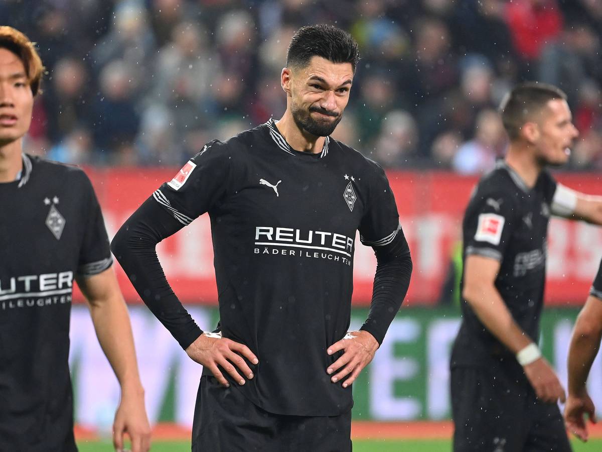 Borussia Mönchengladbachs Stürmer Tim Kleindienst steht nach dem Spiel beim FC Augsburg auf dem Rasen, hat die Arme in die Hüften gestemmt und verzieht das Gesicht.