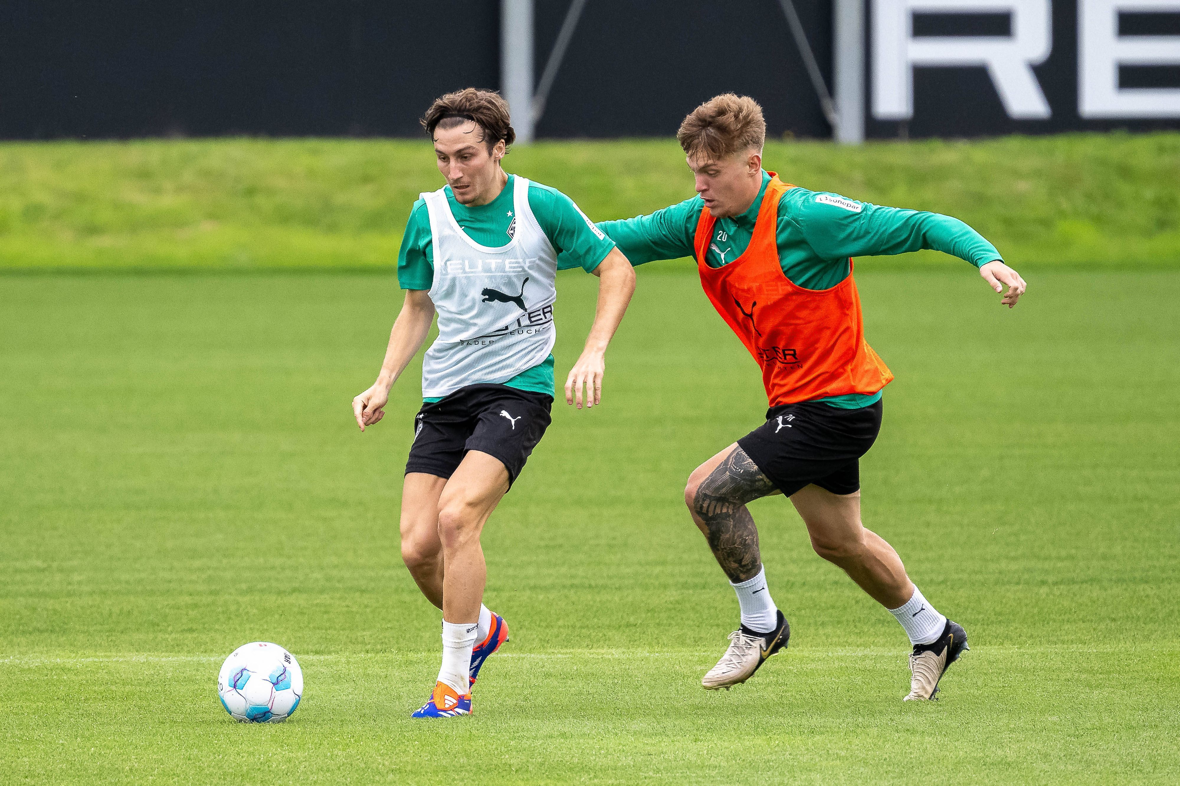 Borussia Mönchengladbachs Rocco Reitz führt den Ball im Training, Teamkollege Luca Netz verfolgt ihn.