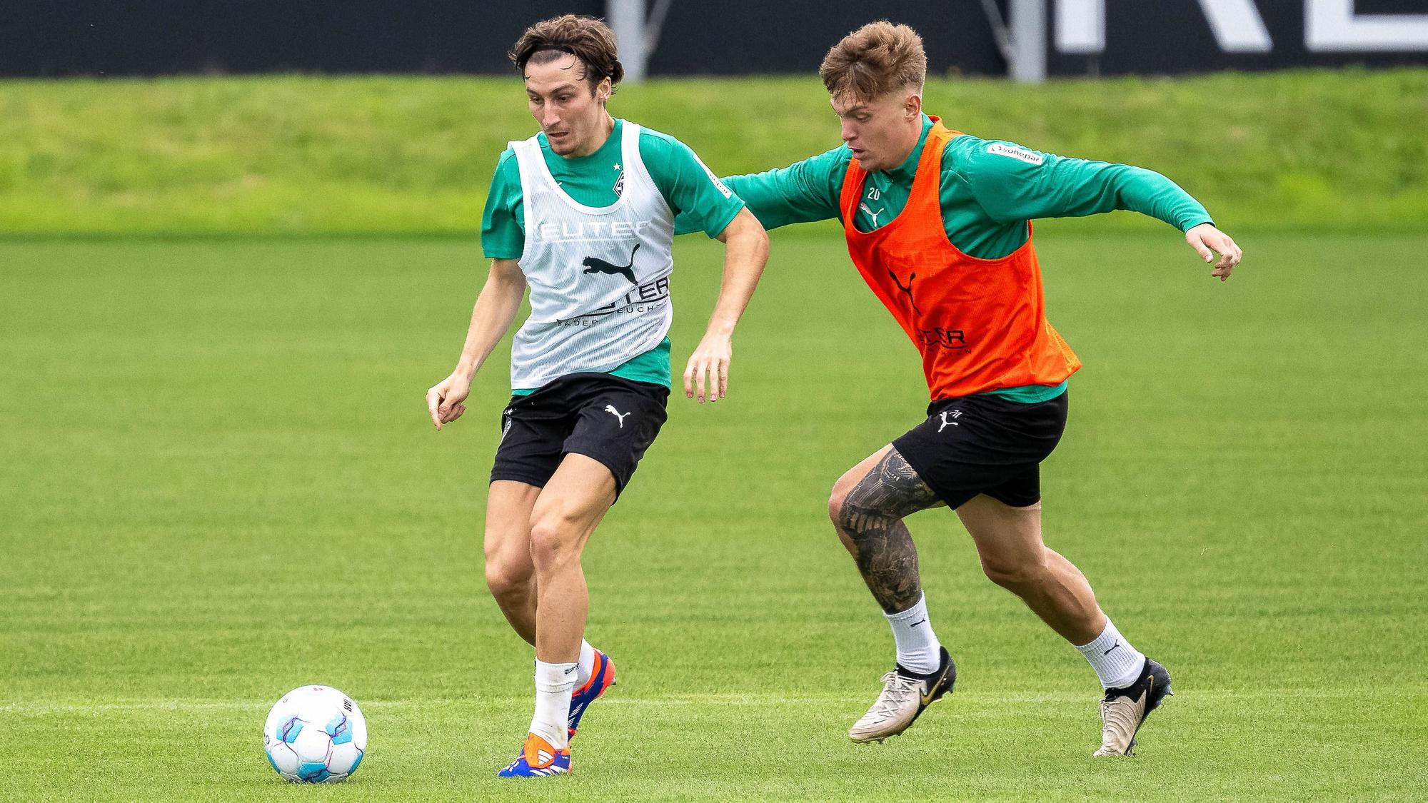 Borussia Mönchengladbachs Rocco Reitz führt den Ball im Training, Teamkollege Luca Netz verfolgt ihn.