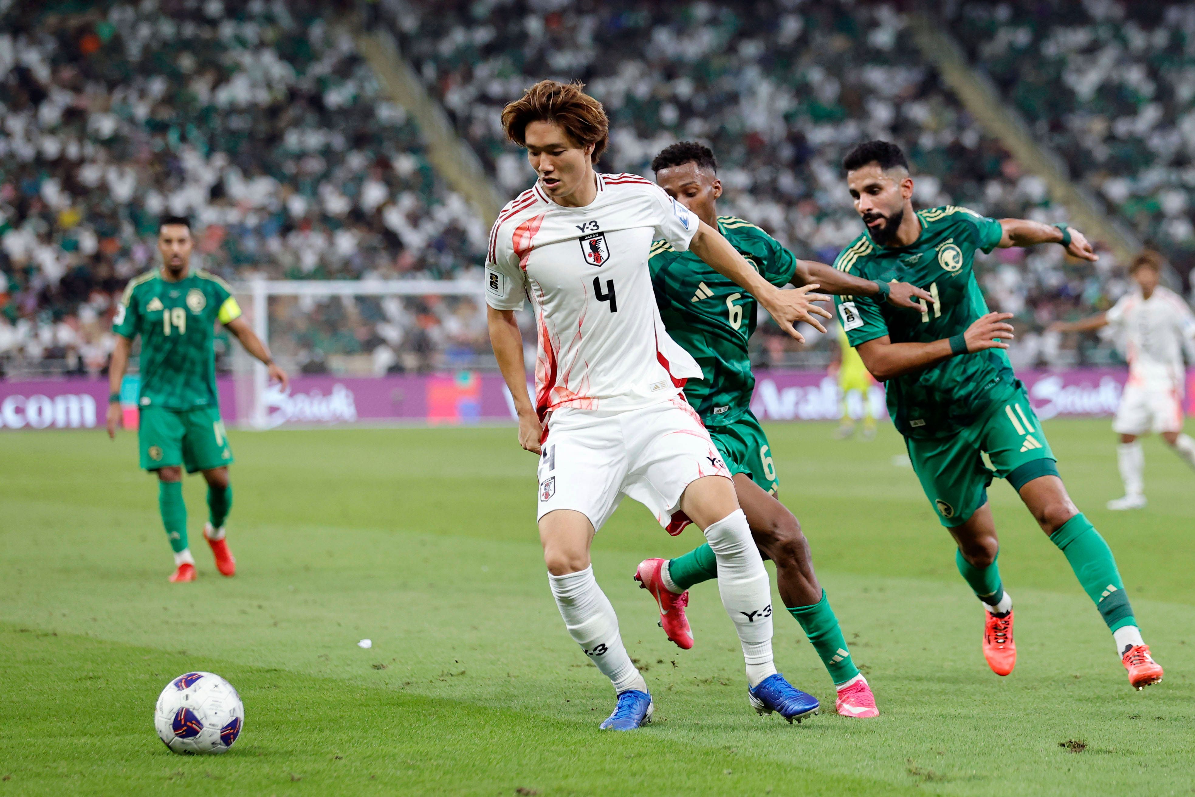 Ko Itakura behauptet den Ball gegen zwei Gegenspieler im Nationaltrikot.