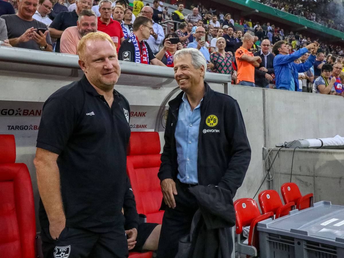 Uerdingens Trainer Heiko Vogel und Dortmunds Trainer Lucien Favre stehen vor dem Pokalspiel lachend nebeneinander an der Trainerbank.