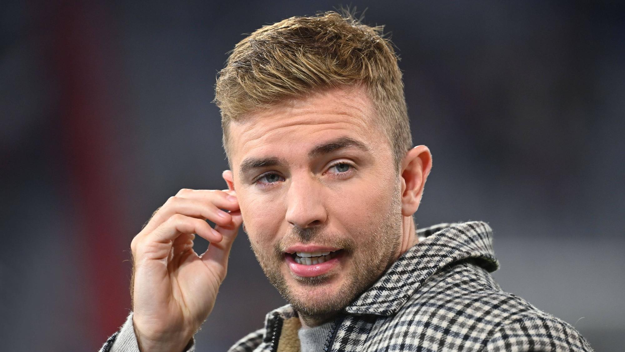 TV-Experte Christoph Kramer steht beim Länderspiel Deutschland gegen die Niederlande im Stadion und greift sich ans Ohr.